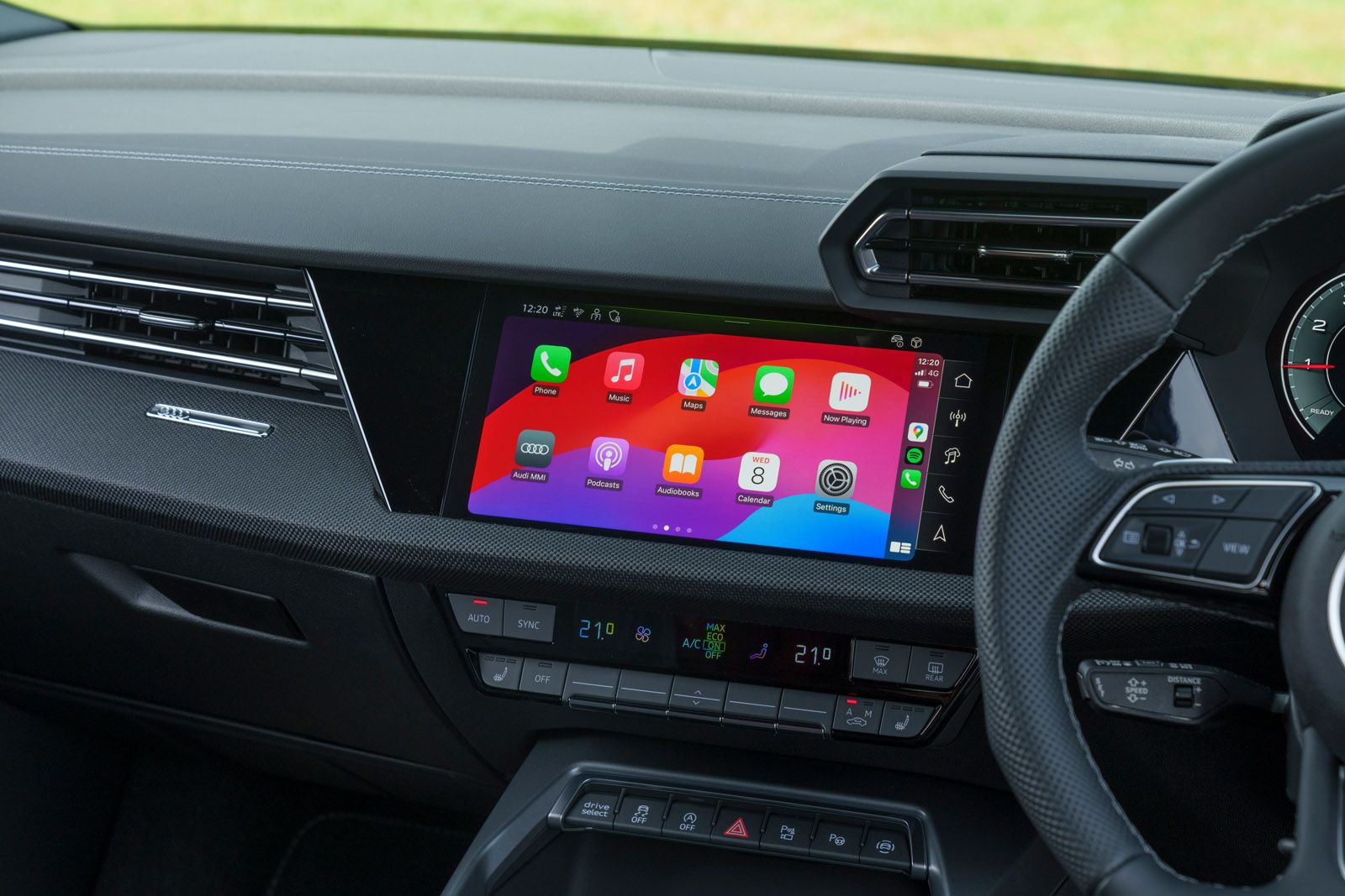 Car dashboard with a digital display showing apps like music, maps, and messages. Buttons and controls are visible below the screen.