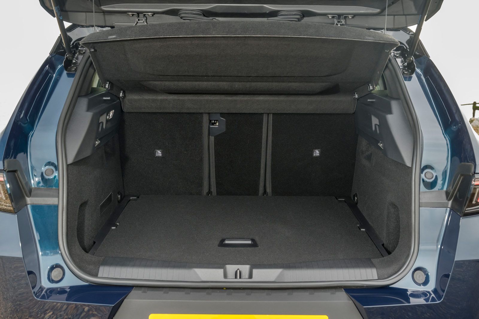 Open rear trunk of a car showing spacious, empty interior with folded seats and a clean, black lining.