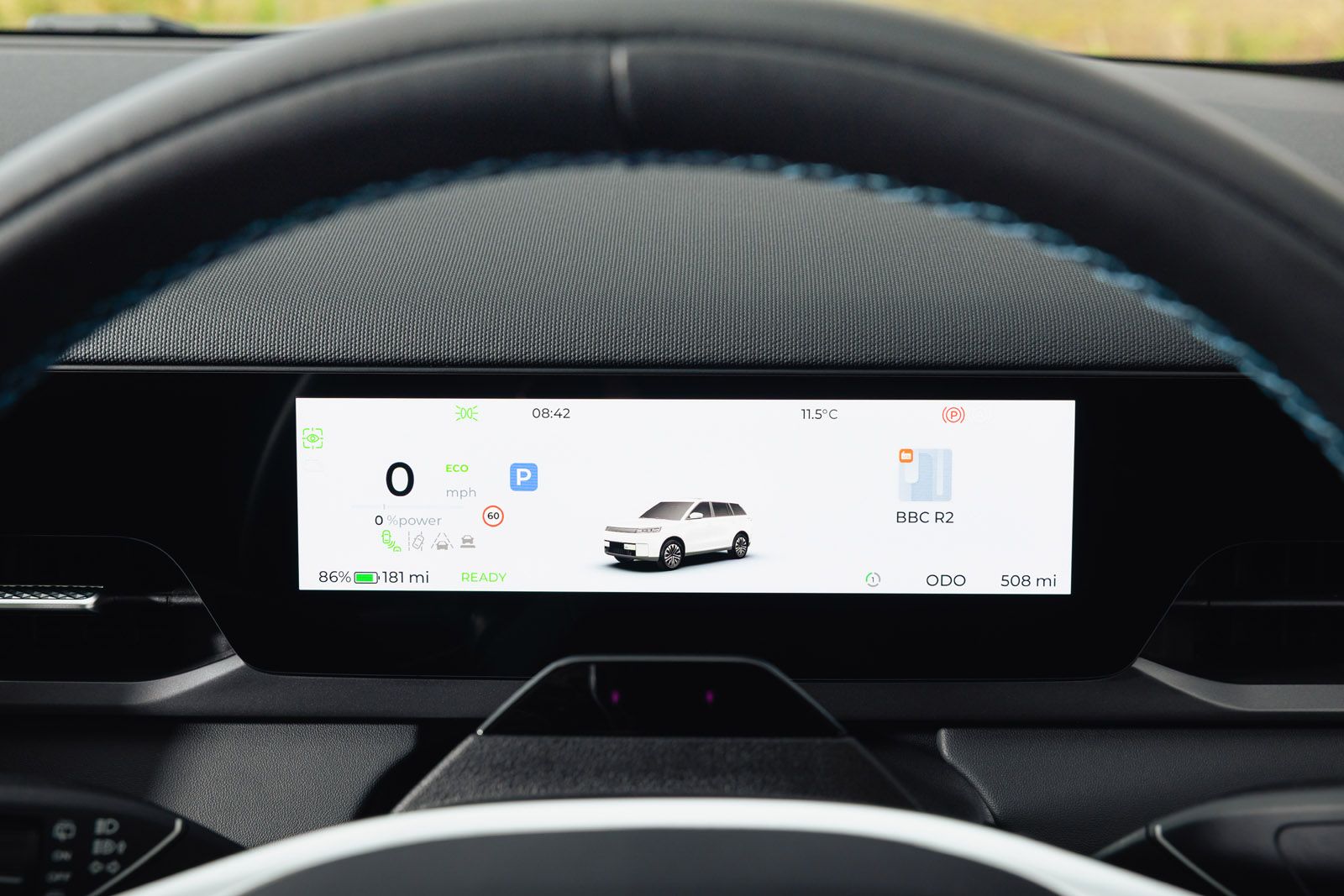 Close-up of a JAECOO E5's digital dashboard displaying 0 mph, battery at 86%, range of 181 miles, and a temperature of 11.5°C.