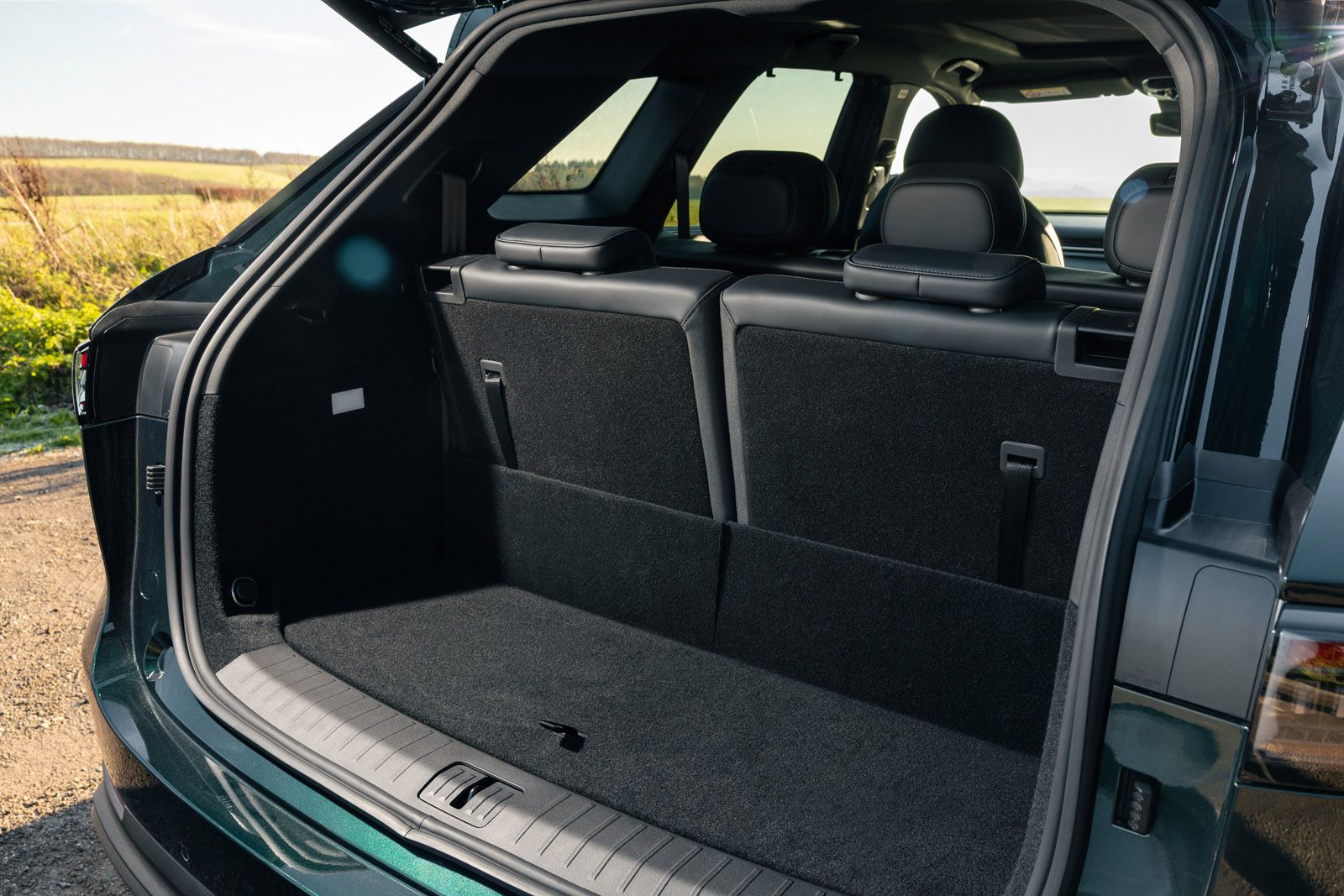Open SUV trunk with rear seats folded up, showing a spacious cargo area. Outdoor scenery visible in the background through the windows.