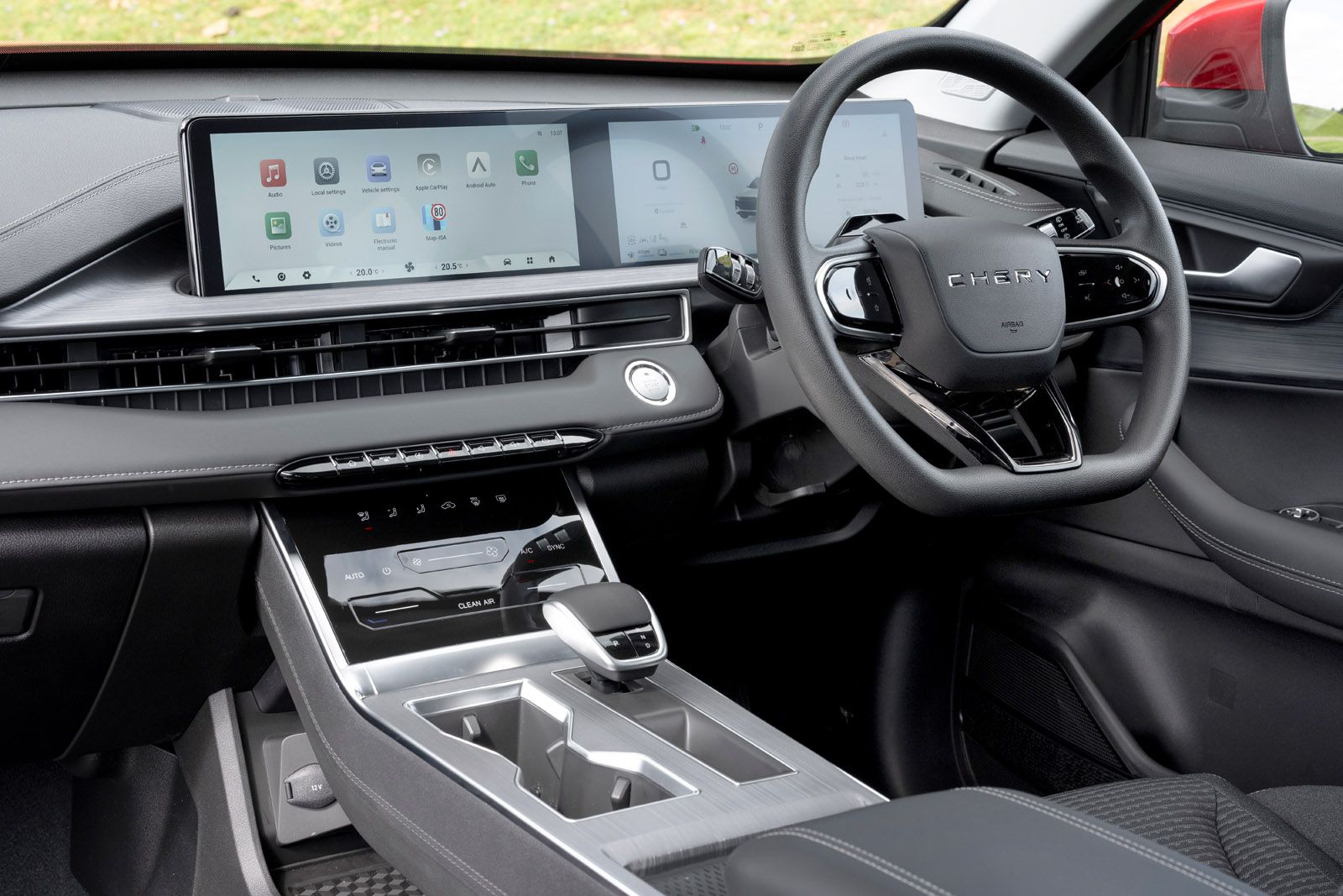 Modern car interior with a large touchscreen display, multifunction steering wheel, sleek dashboard, and center console with gear selector.