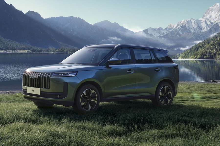 JAECOO J5 parked on grass next to a lake and snowy mountains