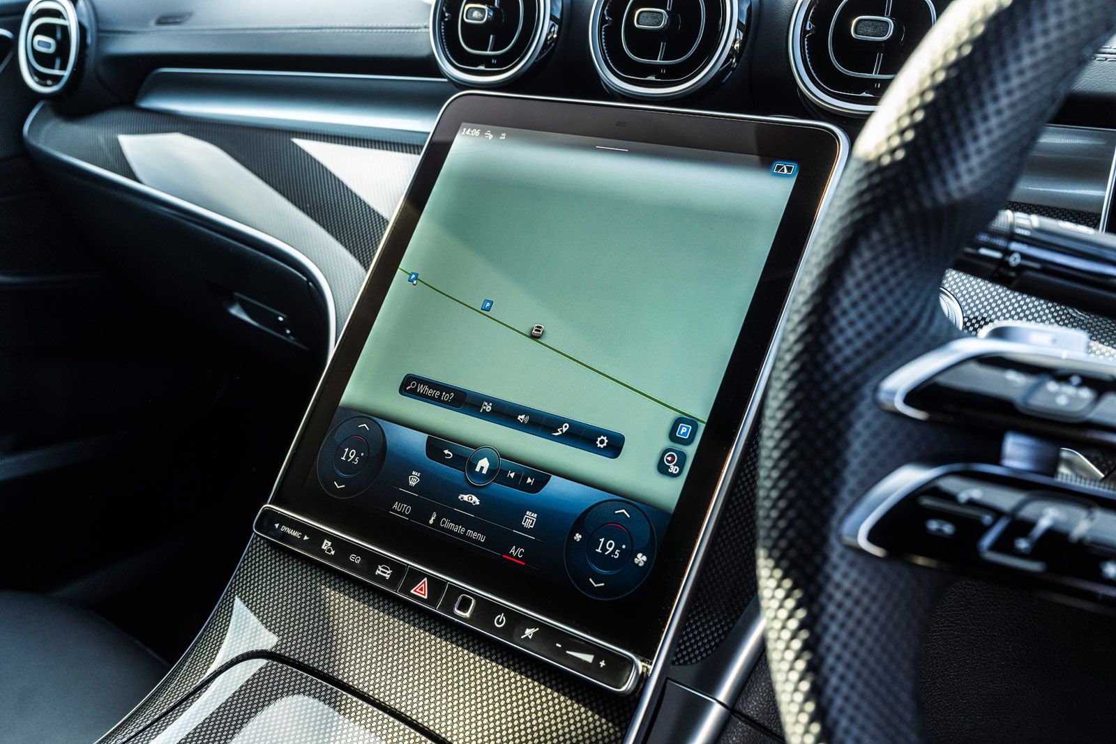 Car interior showing a large touchscreen with navigation display, surrounded by a sleek dashboard and steering wheel with modern controls.