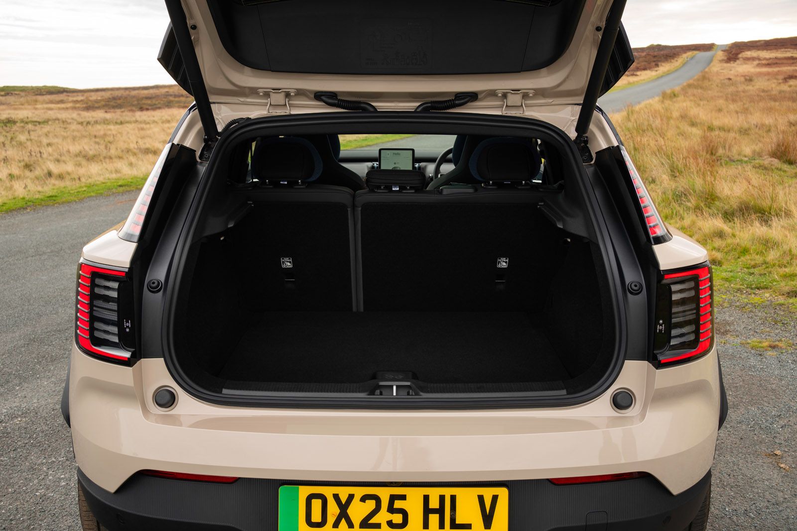 Open trunk of a beige SUV on a rural road, showing a spacious cargo area with folded rear seats.