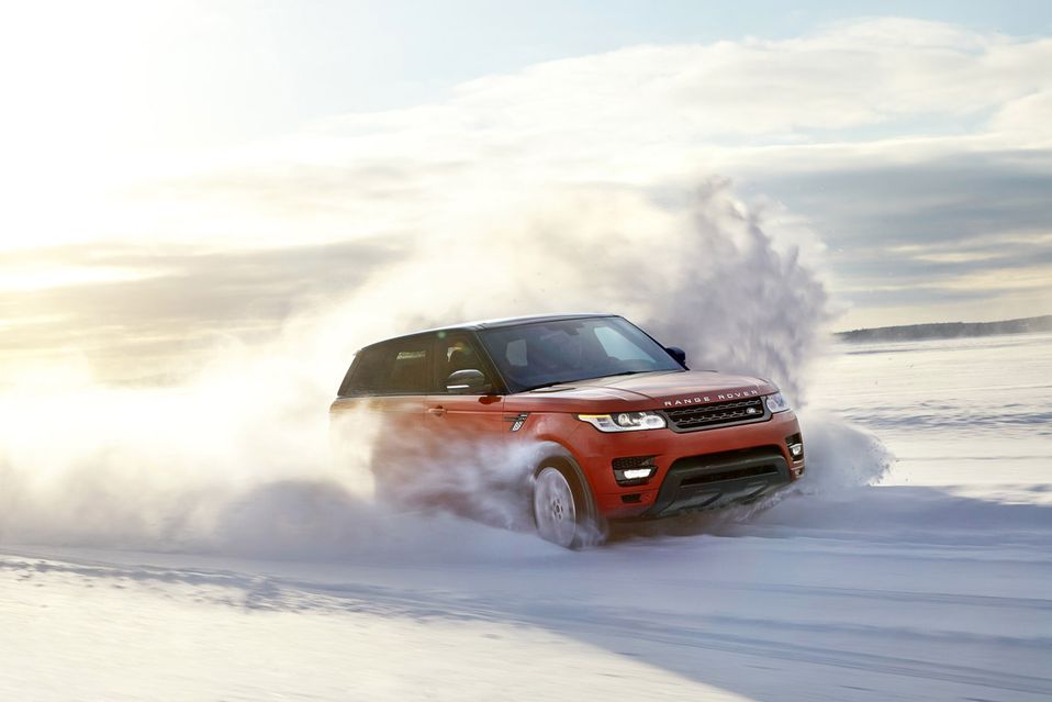 an orange Range Rover Sport driving in the snow