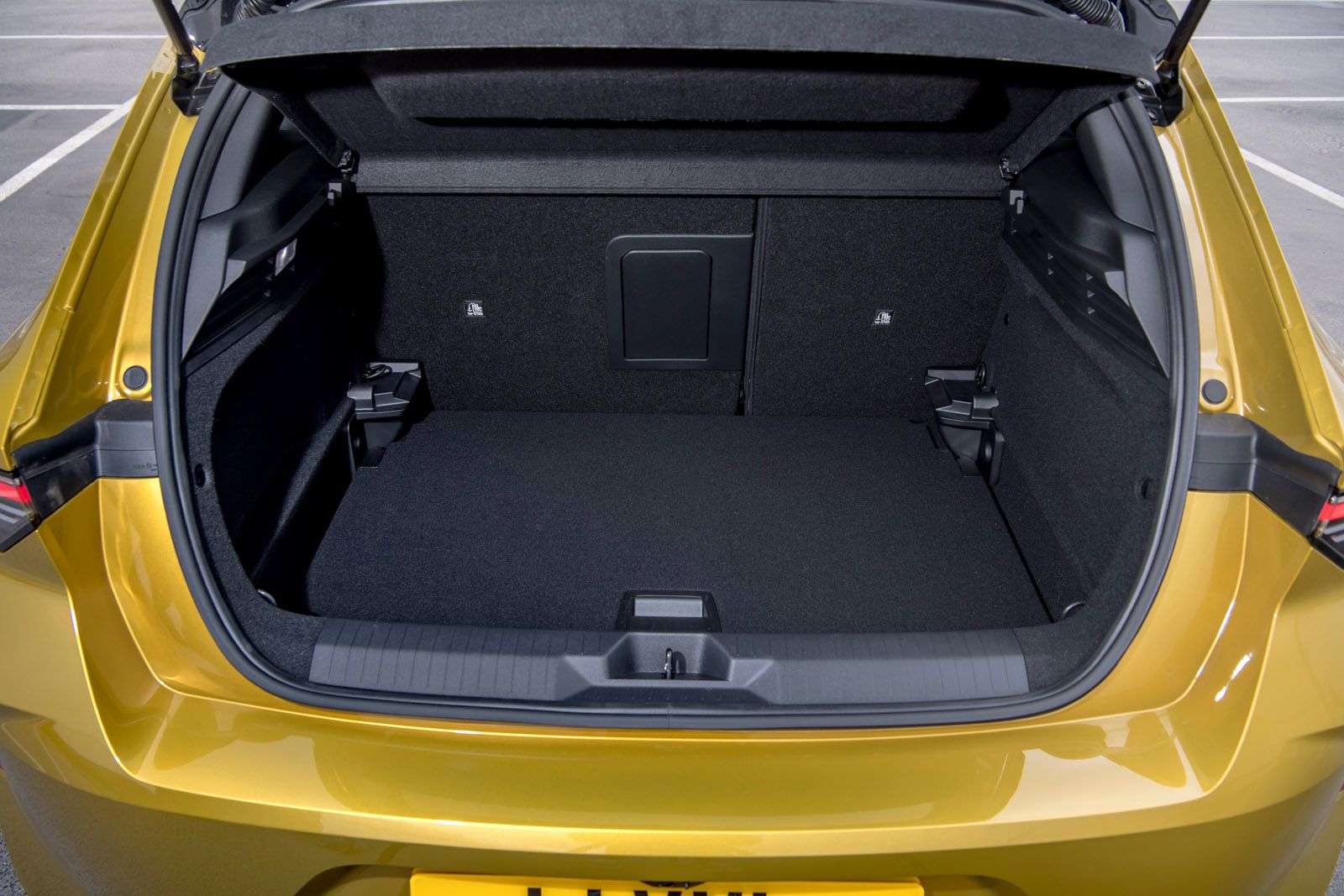 The open trunk of a yellow car showing a spacious, empty cargo area with a foldable back seat.