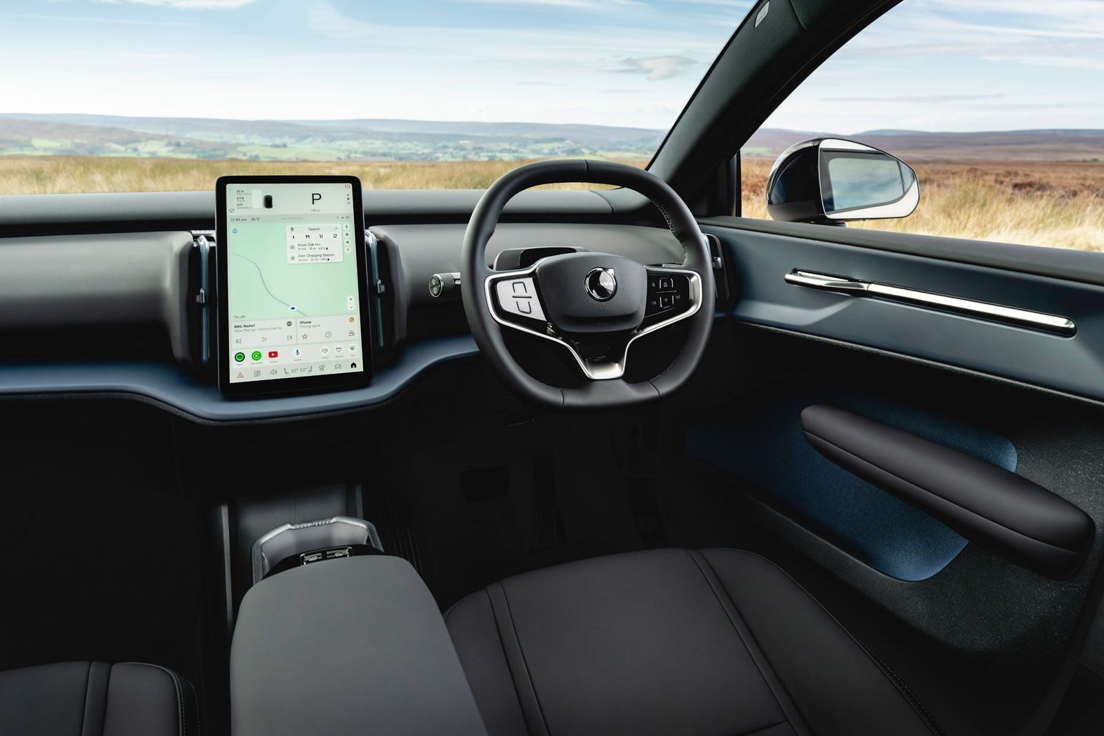 Modern car interior with a touchscreen display showing a map, sleek steering wheel, and scenic view through the window.