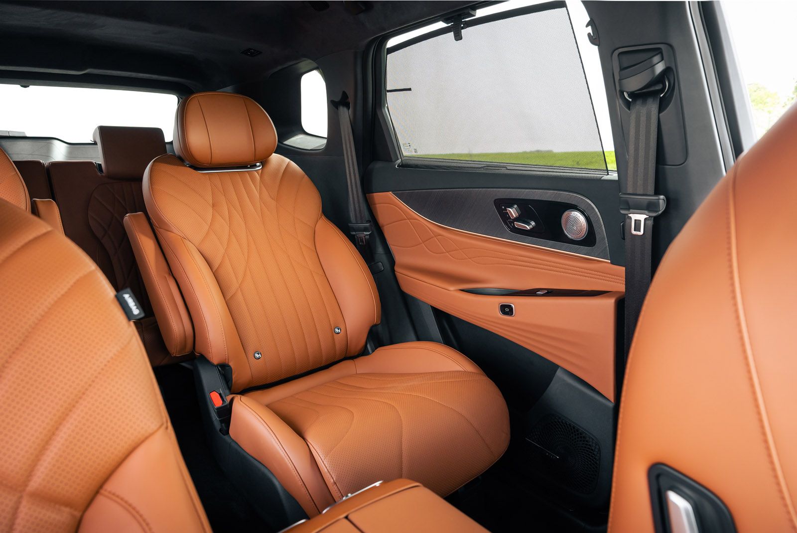Luxurious car interior with tan leather seats, detailed stitching, and door panel. The window is partially open, revealing a sleek design.