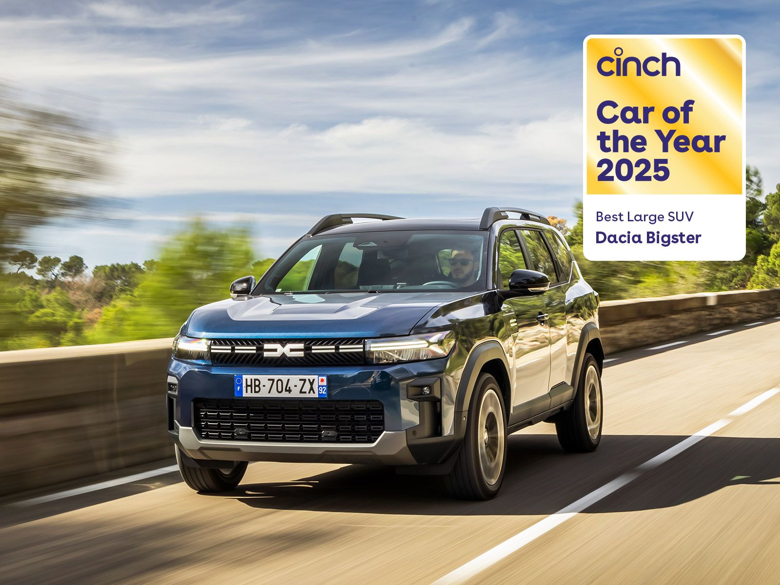 A Dacia Bigster SUV driving on a road, with a "Cinch Car of the Year 2025" badge for Best Large SUV displayed in the top right corner.