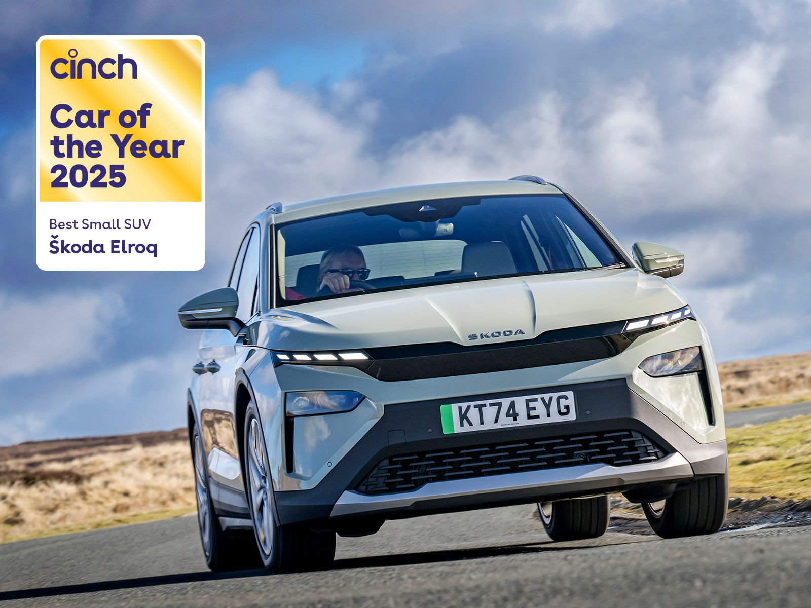 A white Škoda Elroq SUV driving on a road with a "Car of the Year 2025" award badge displayed in the top left corner.