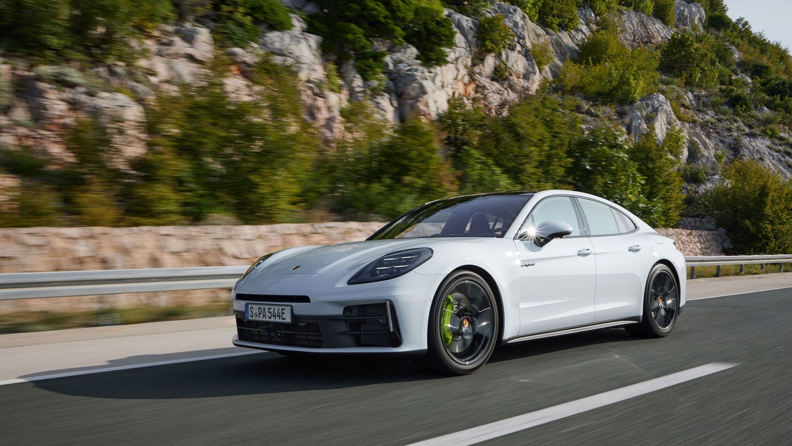 white Porsche Panamera driving on a road near a mountain