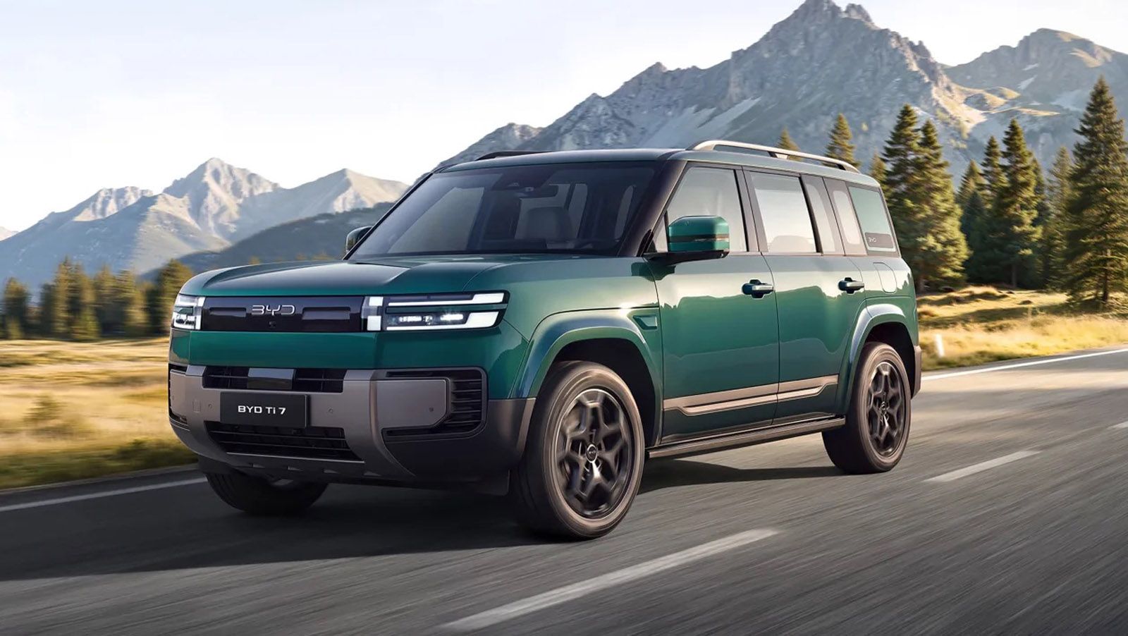 Green BYD SUV driving on a highway with mountains and pine trees in the background.