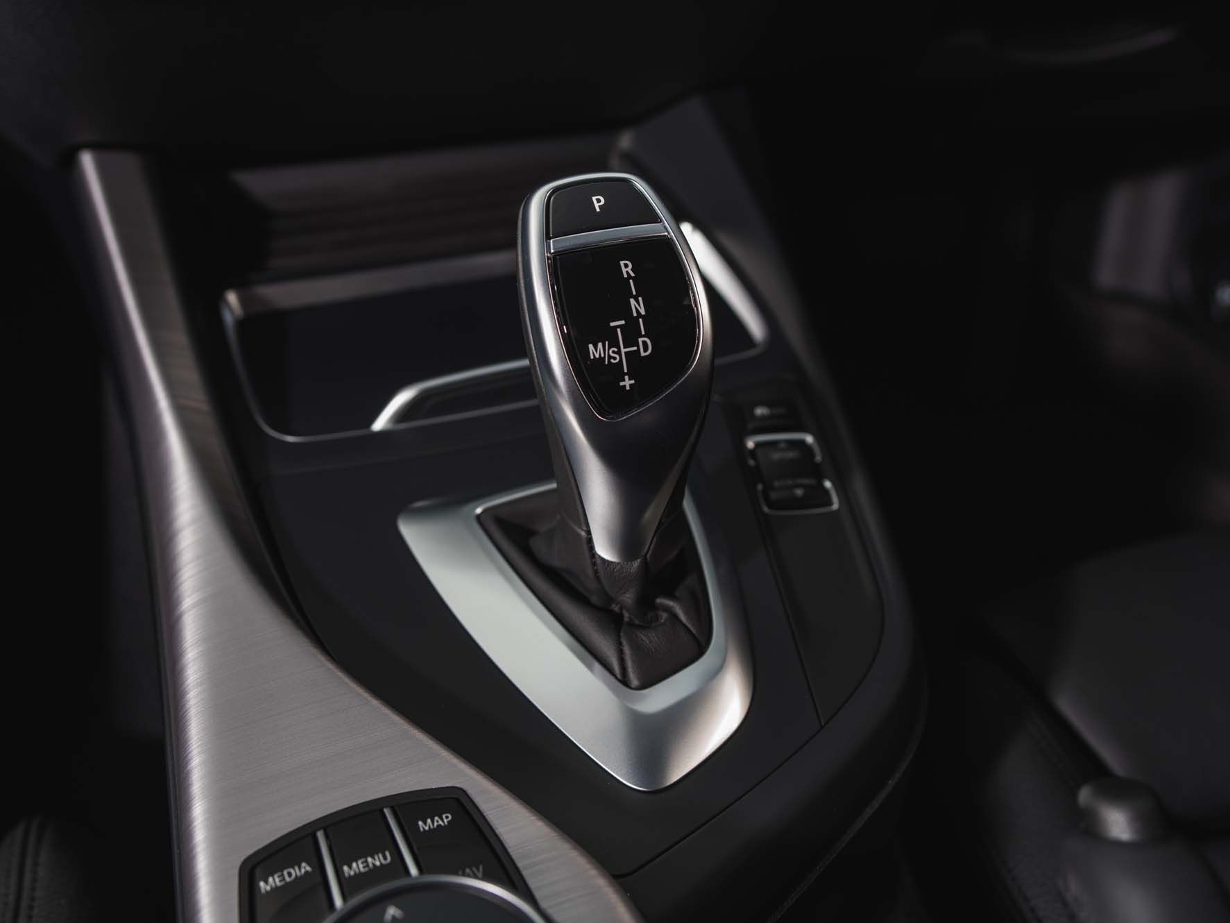 Close-up of a BMW 2 Series gear shift lever in a sleek, high-tech centre console, showing park, reverse, neutral, drive, and manual shift options.