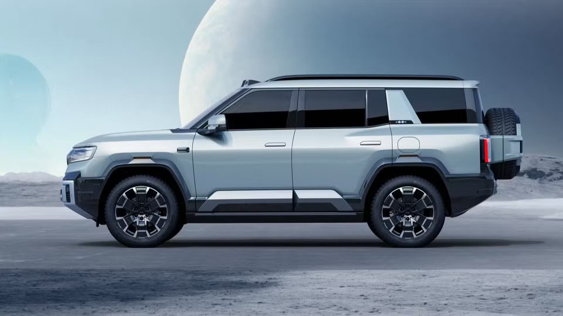 Silver SUV with black trim parked on a flat, moon-like surface. Large tires and sleek design set against a sky featuring a prominent moon.