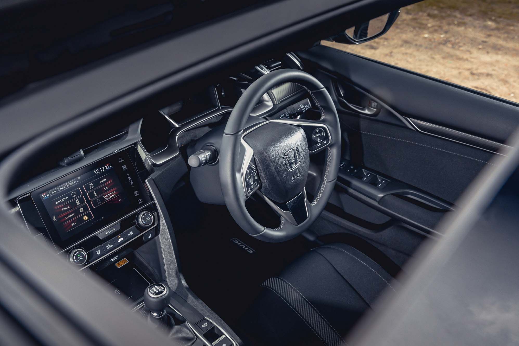 Interior view of a Honda Civic showing a steering wheel with the Honda logo, digital dashboard, and touchscreen display on the center console.