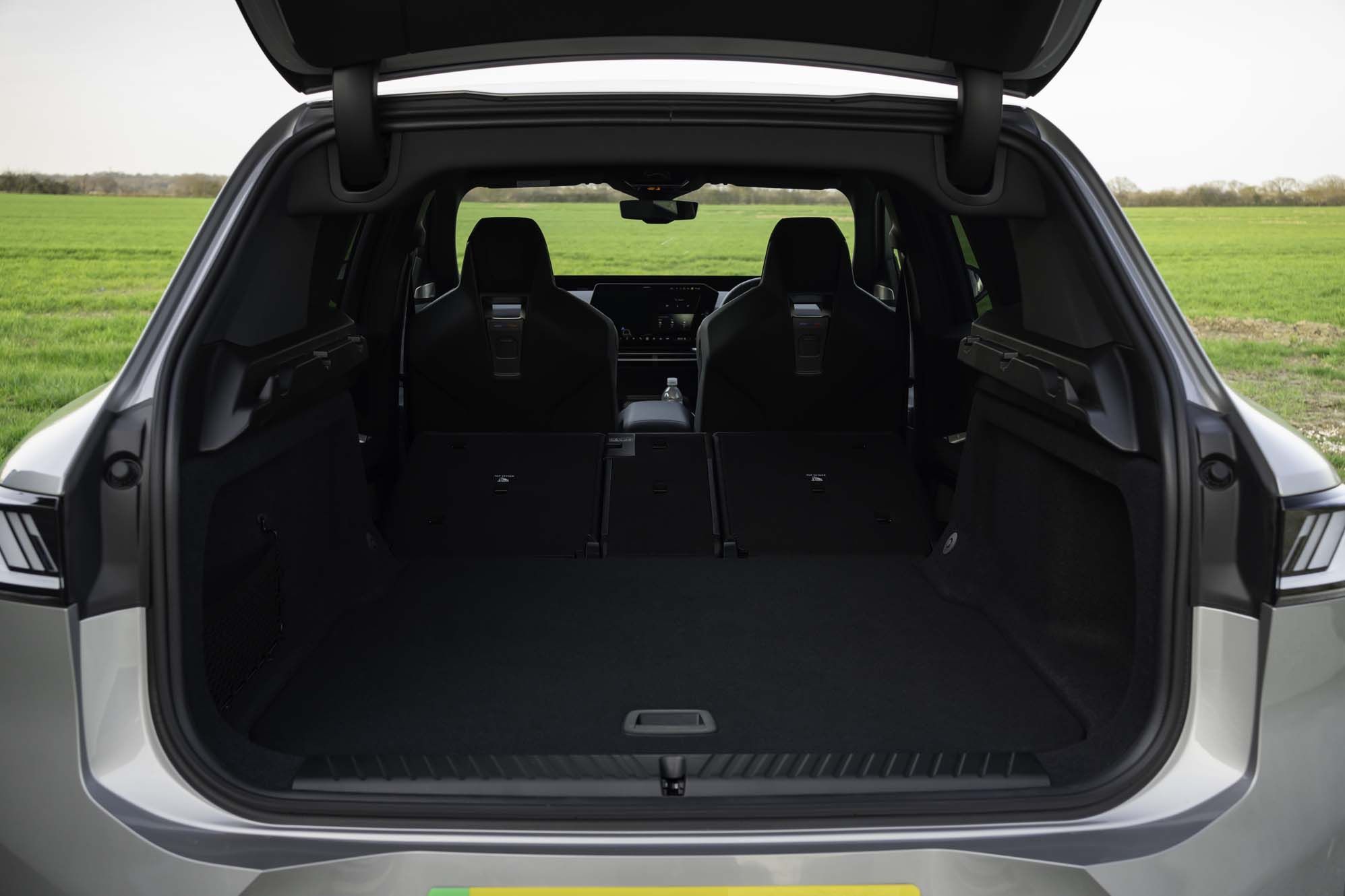 Open boot of a BMW iX3 with rear seats folded, revealing a spacious cargo area, with a view of the front seats and dashboard.