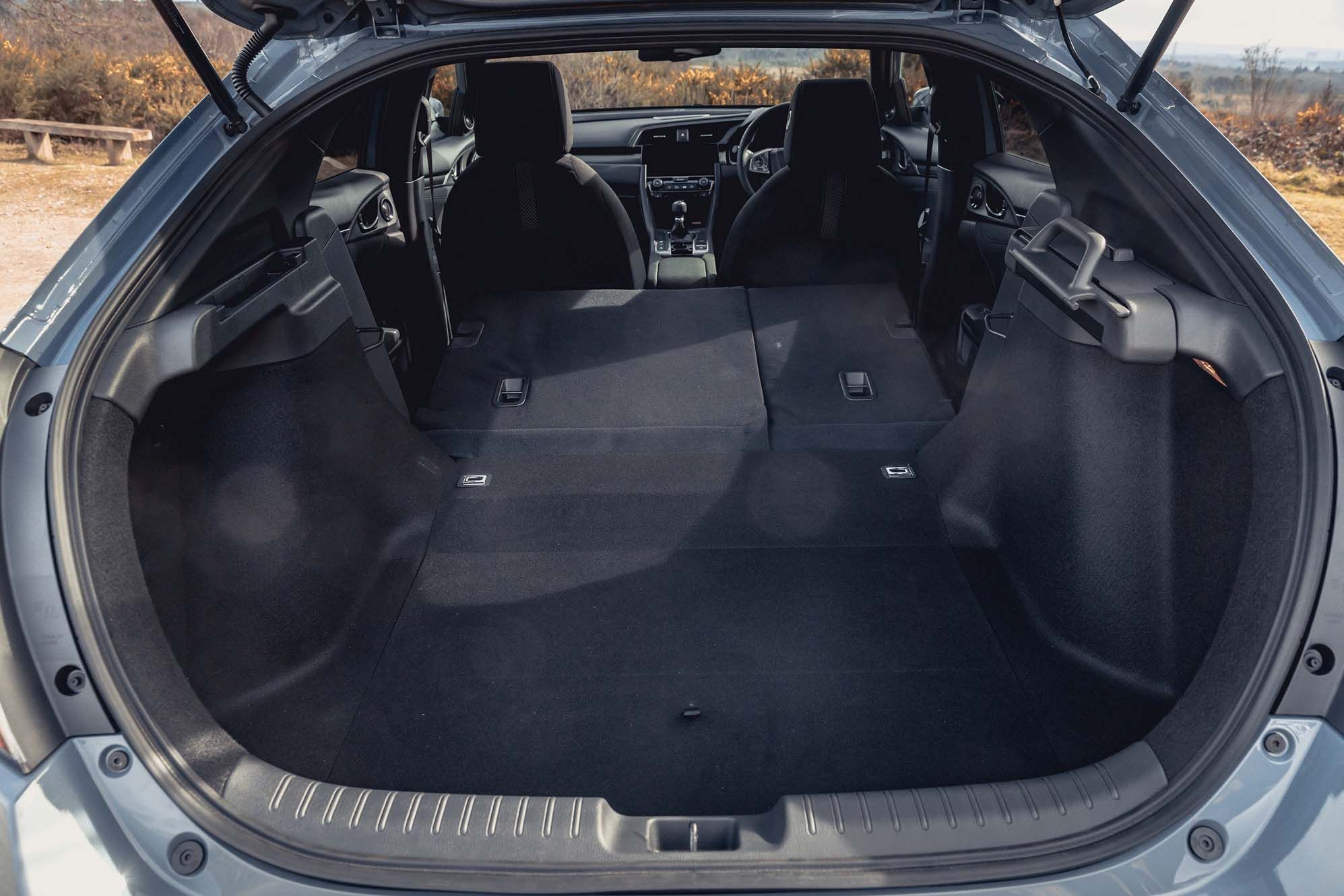 Open Honda Civic boot with rear seats folded down, creating a spacious cargo area. Interior is clean and modern with visible dashboard controls.