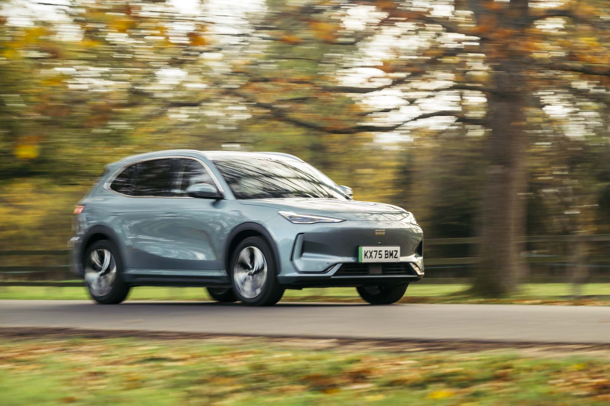 Geely EX5 driving on a road with blurred autumn trees in the background.