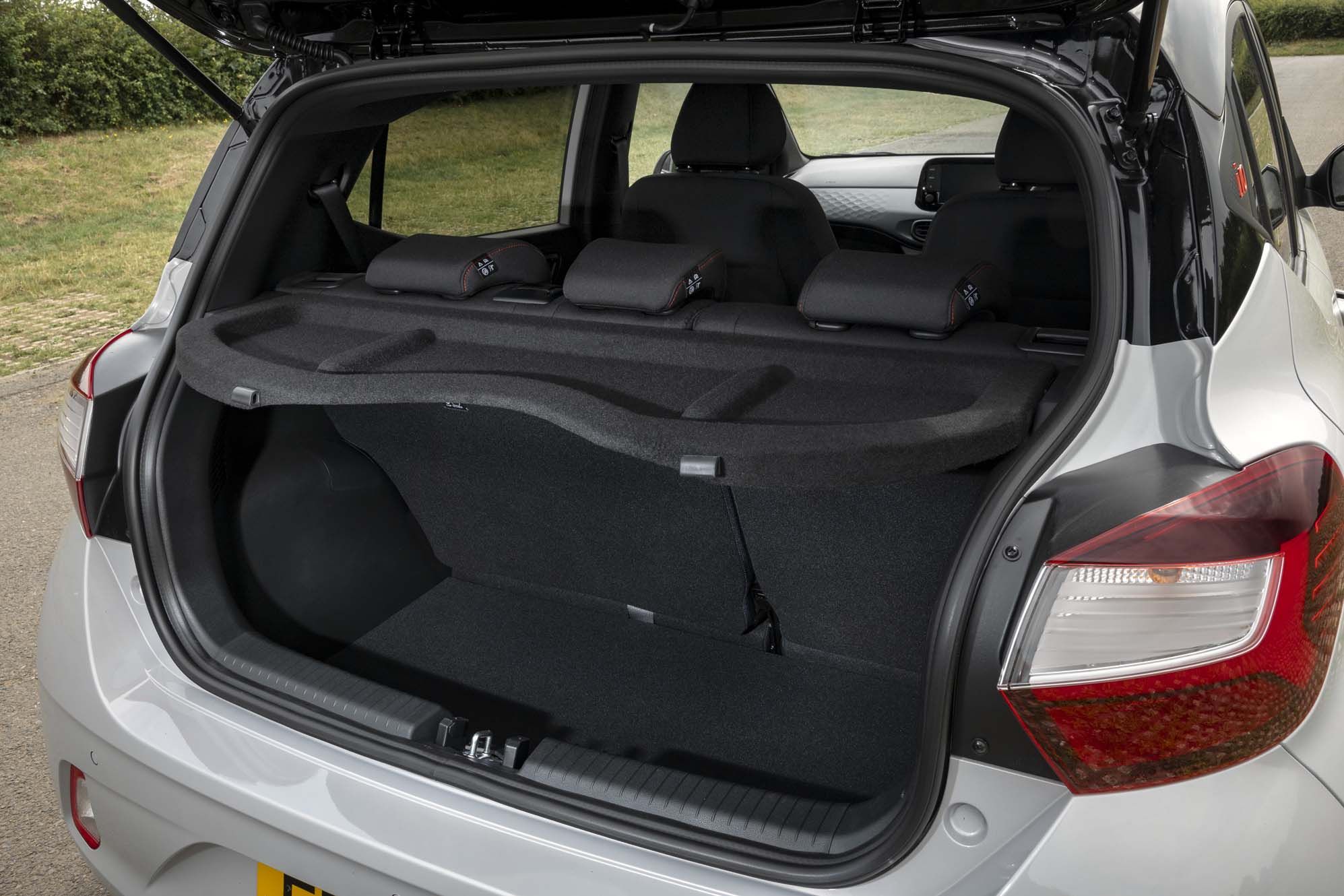 Open boot of a Hyundai i10, parked on a road with grass in the background.