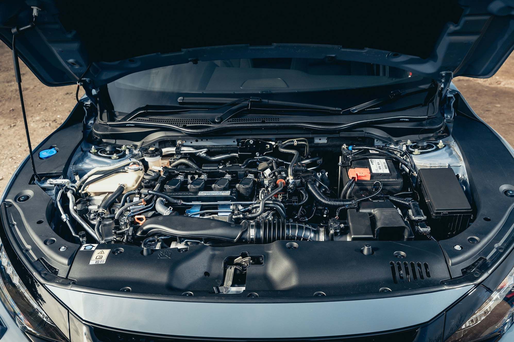 Honda Civic engine engine with open bonnet showing various components, including battery, hoses, and metal parts, in a well-organised layout.