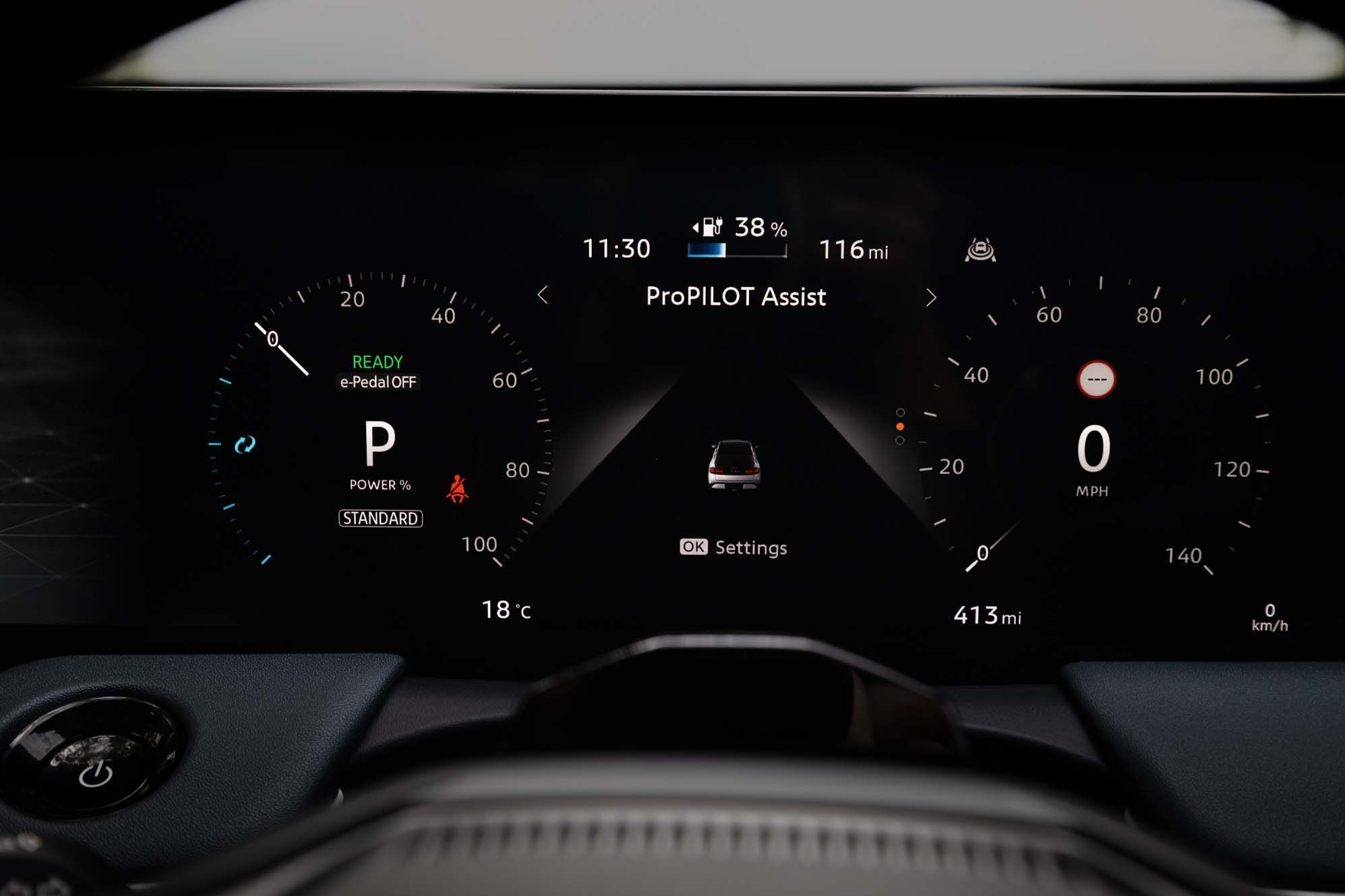Close-up of a Nissan LEAF dashboard displaying digital indicators: parking mode, ProPILOT Assist, battery at 38%, range of 116 miles, and speed at 0 mph.