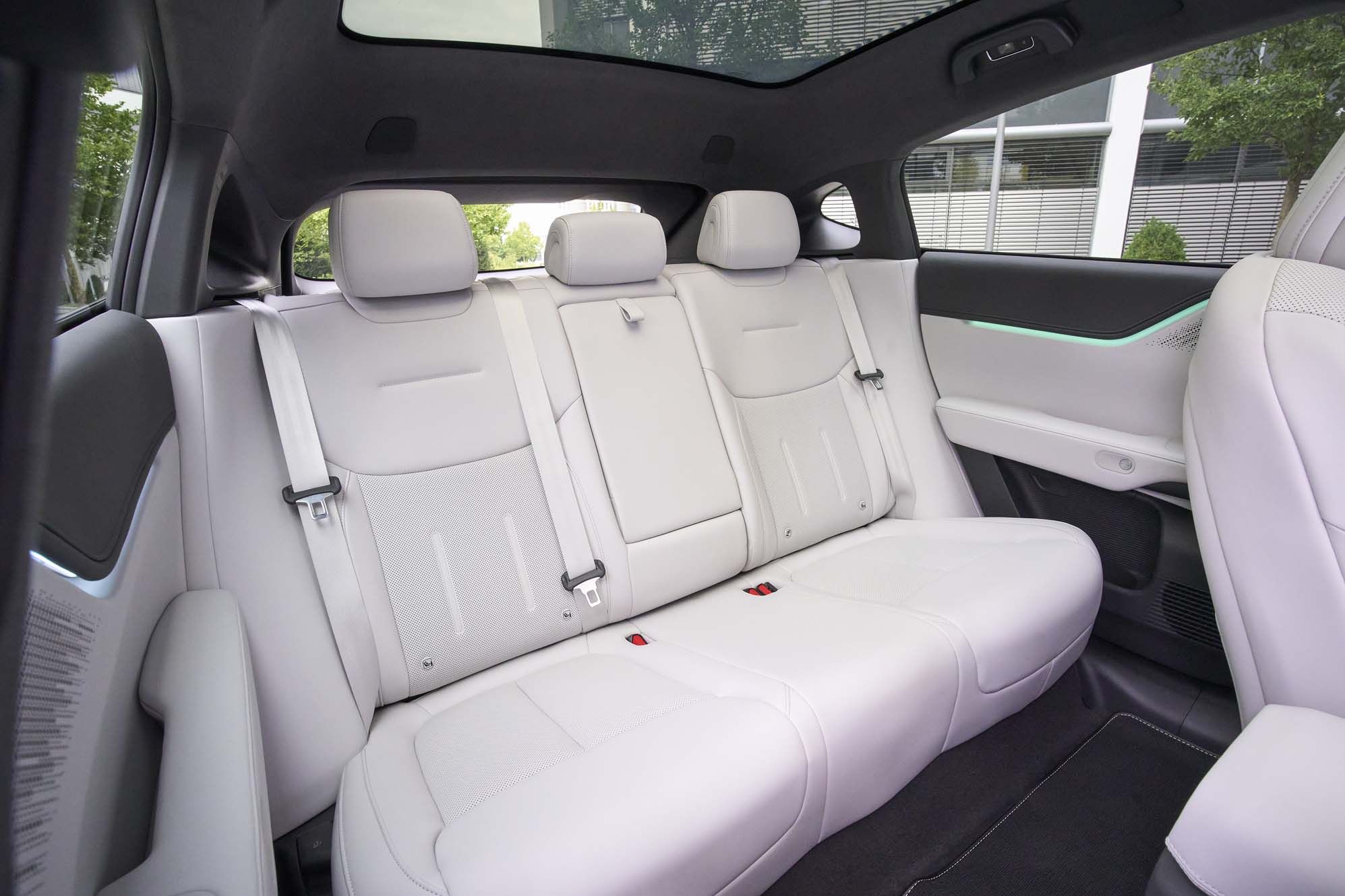 XPENG G6 interior with white leather rear seats, three headrests, and black accents. Panoramic sunroof and LED trim detail are visible.