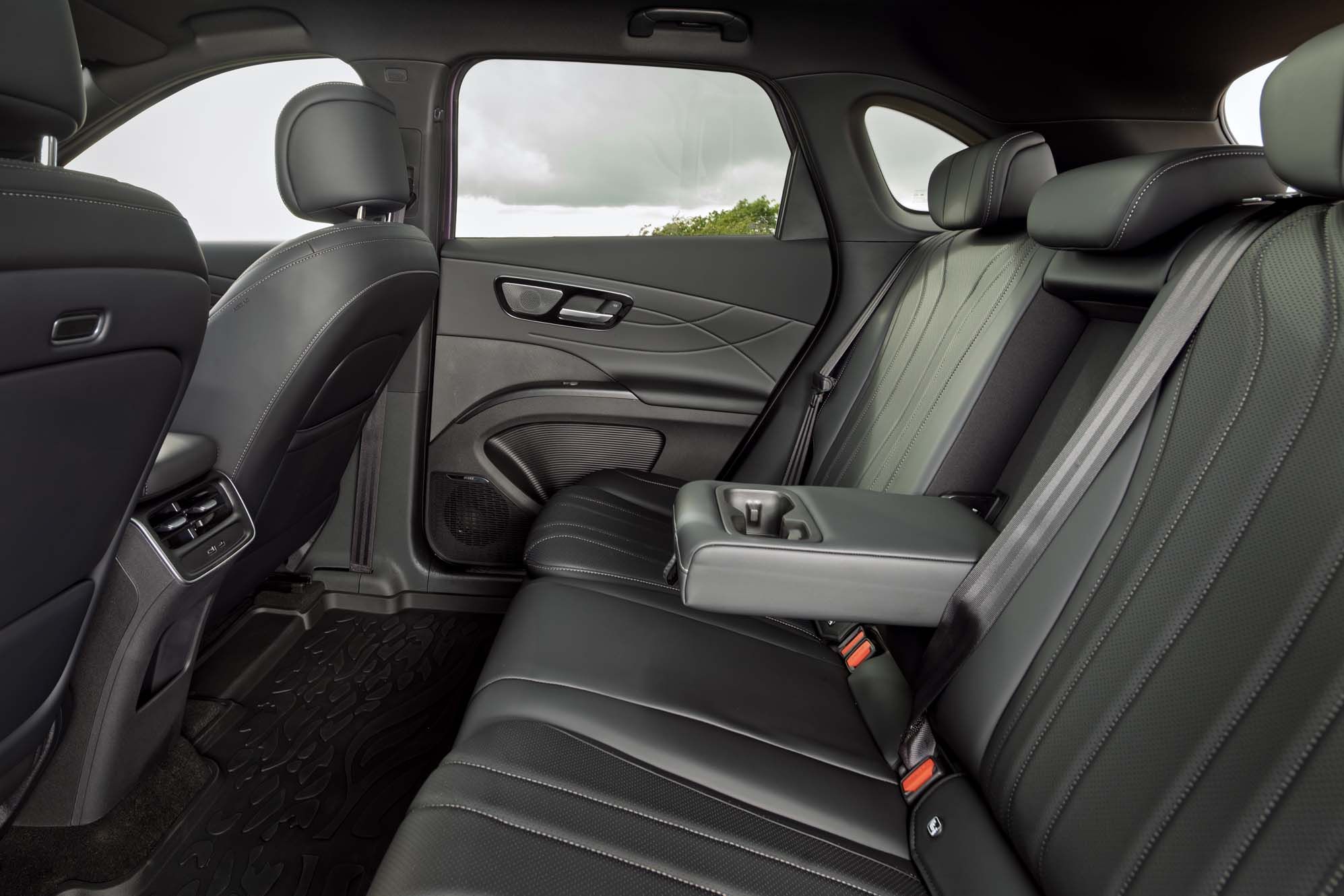 Interior of a LEPAS L8's backseat featuring black leather seats, an armrest with cup holders, and elegant door panel design.