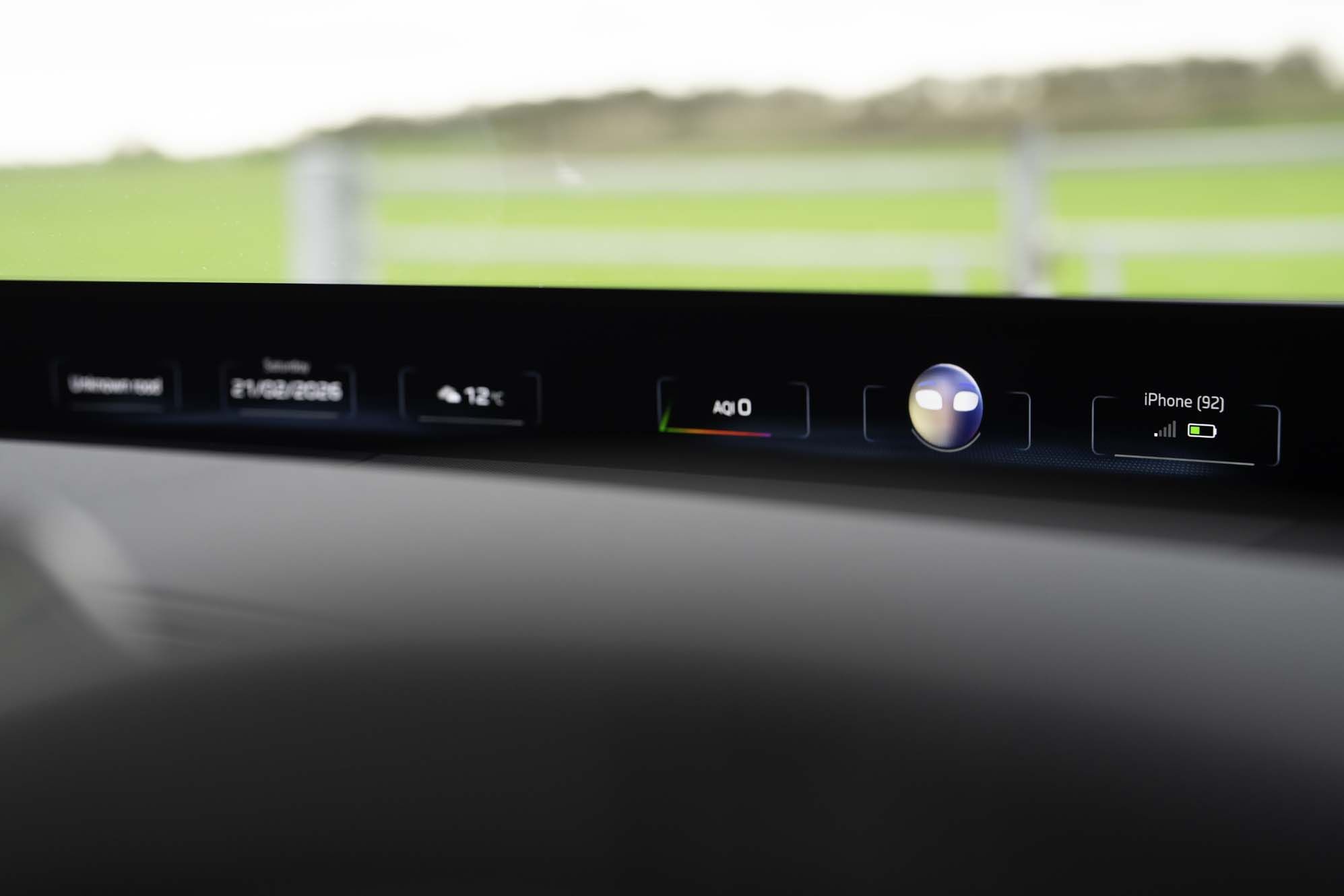 BMW iX3 dashboard display showing date, temperature, air quality index, digital assistant icon, and connected iPhone status.