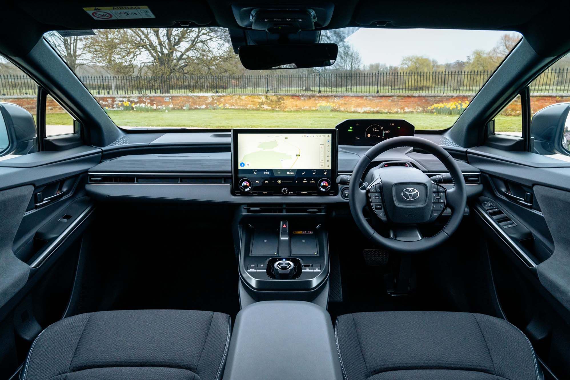 Interior of a Toyota C-HR+ featuring a sleek dashboard, steering wheel, and a large central touchscreen with navigation displayed.