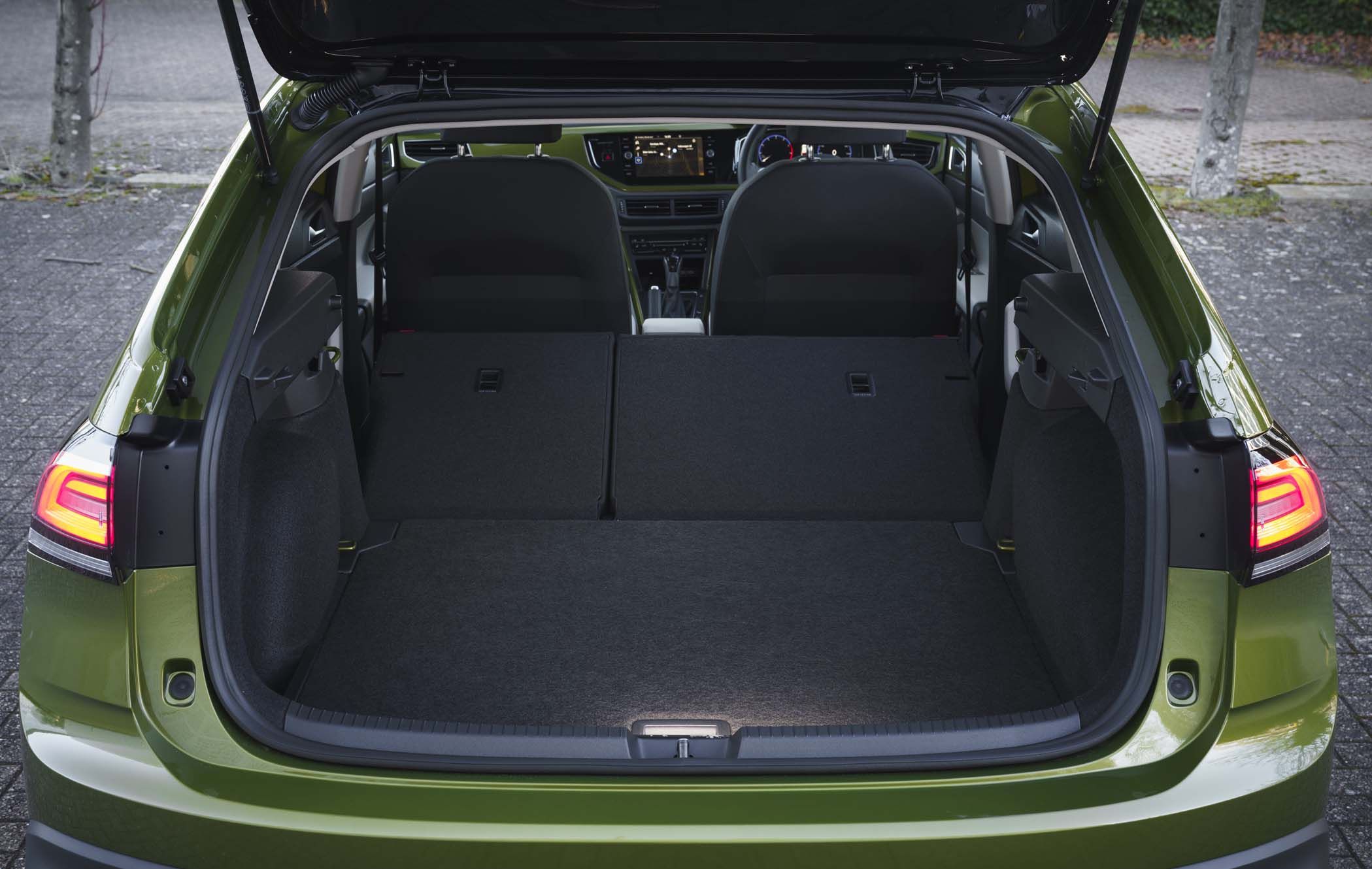 Open boot of a VW Taigo with rear seats folded down, revealing a spacious luggage area. Tail lights are illuminated.