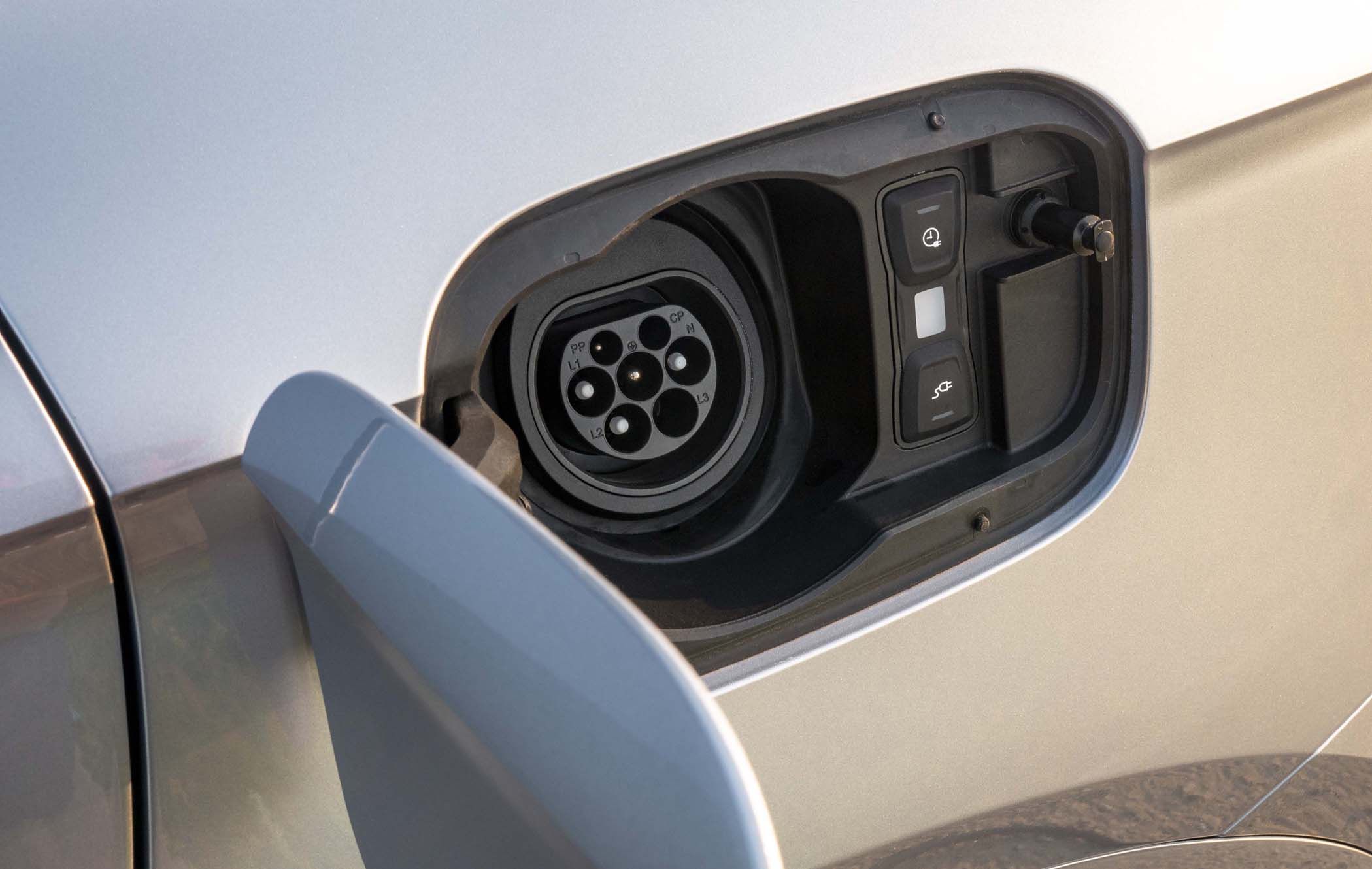 Close-up of an Audi Q5 TFSI e charging port with an open flap, revealing a Type 2 connector and charging buttons on a silver car.