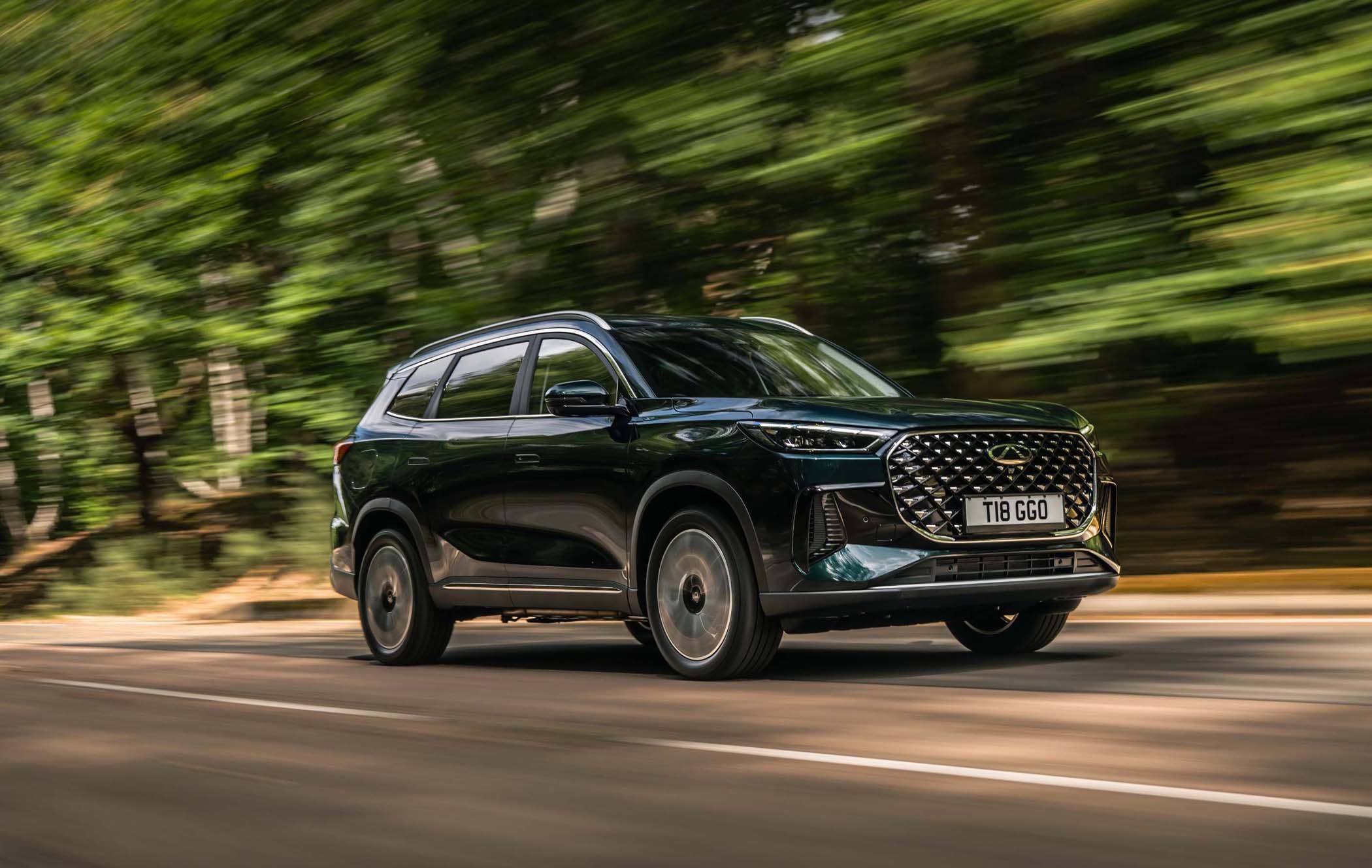 A Chery Tiggo 8 Super Hybrid driving on a road with blurred green trees in the background, conveying speed and motion.