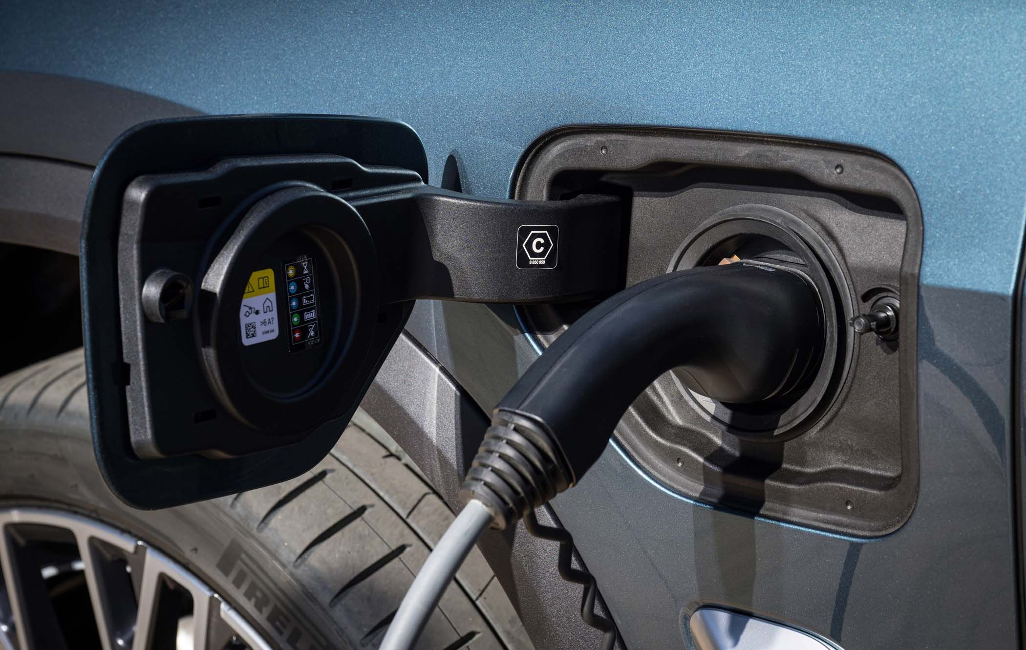 Close-up of a BMW X5 plugged into a charging station, with the charging cable connected to the vehicle’s charging port.