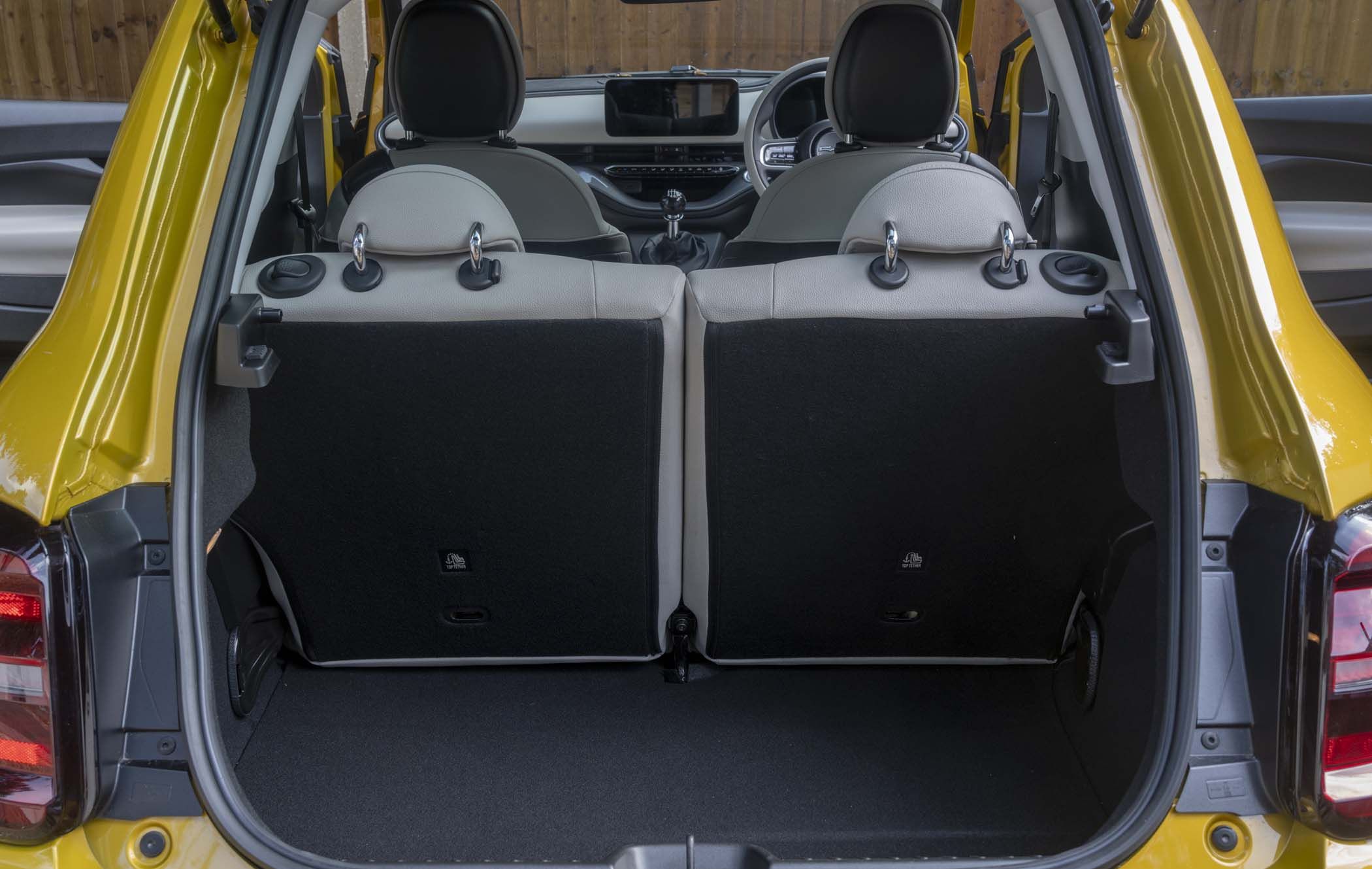 Open boot of a yellow Fiat 500 Hybrid showing rear seats in an upright position and a spacious cargo area with headrests visible.