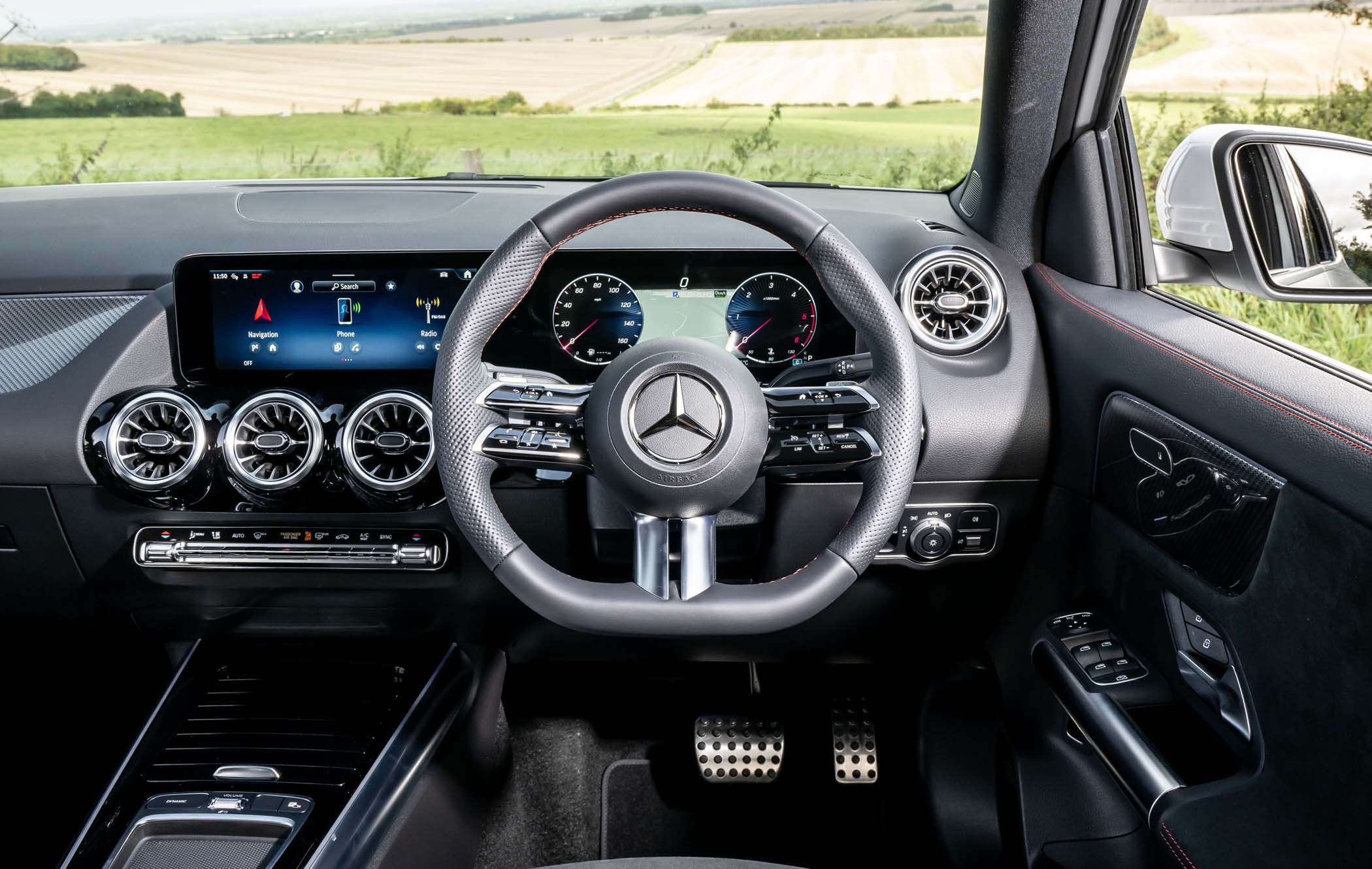 Interior of a Mercedes GLA car showing a detailed dashboard, steering wheel, digital displays, and fields visible through the windshield.