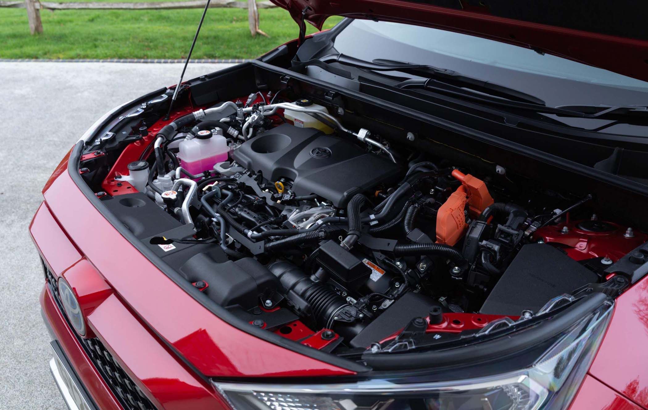 Open bonnet of a red Toyota RAV4 showing a clean, organised engine compartment with visible components and wiring, parked on a concrete surface.