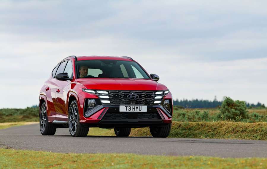 Red Hyundai Tucson N Line driving on country road