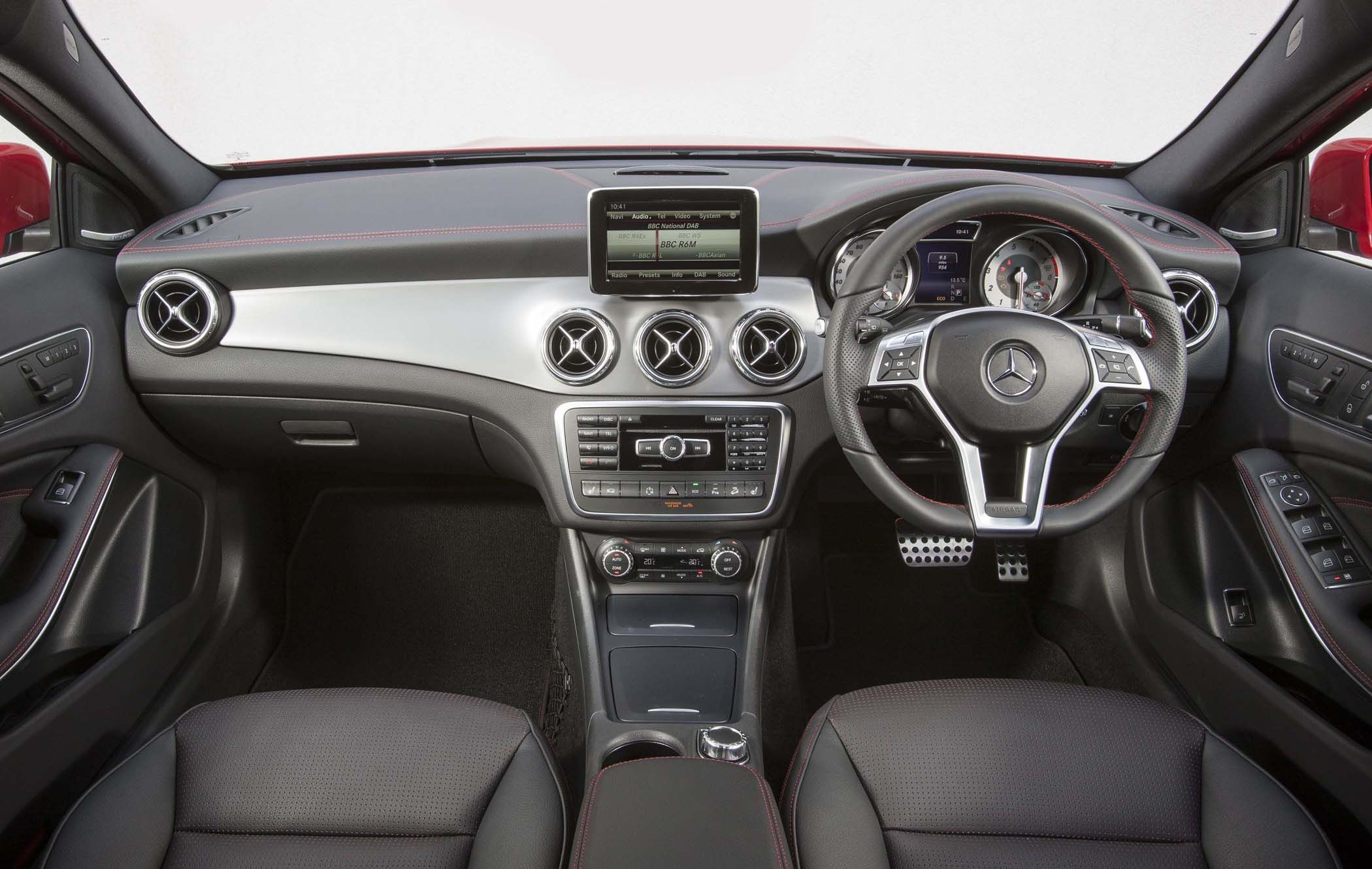 Interior view of a Mercedes GLA's dashboard with a digital display, circular air vents, a leather-wrapped steering wheel, and control panel.