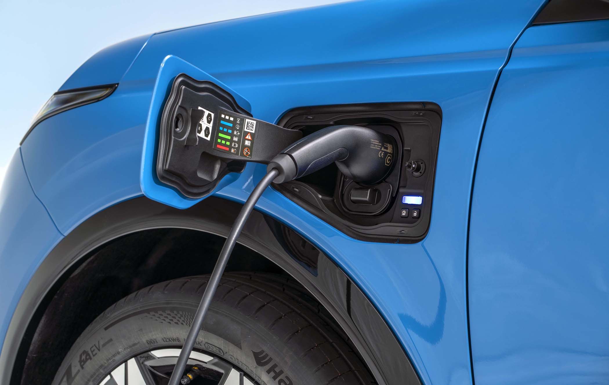 Blue Nissan MICRA charging, close-up of the plug connected to the charging port with visible indicators.