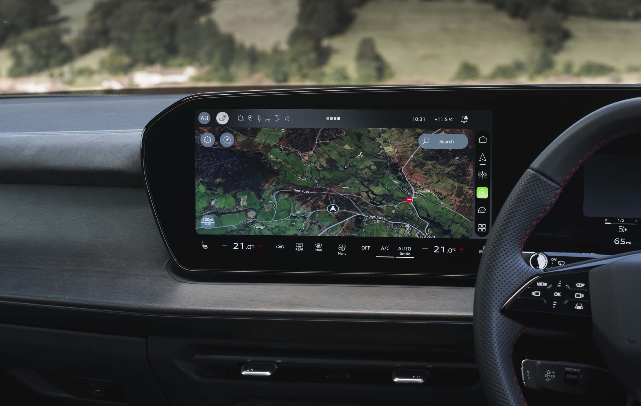 Audi Q3 dashboard with a touchscreen displaying a map, navigation controls, and climate settings; a steering wheel is partially visible.