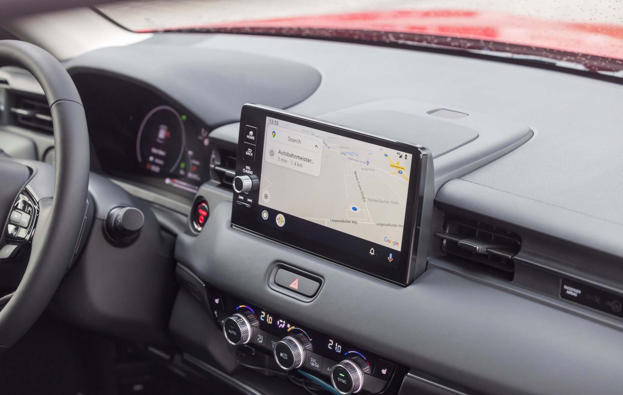 Honda HR-V interior with a touchscreen displaying a navigation map, dashboard controls, and climate settings. Black and gray color scheme.