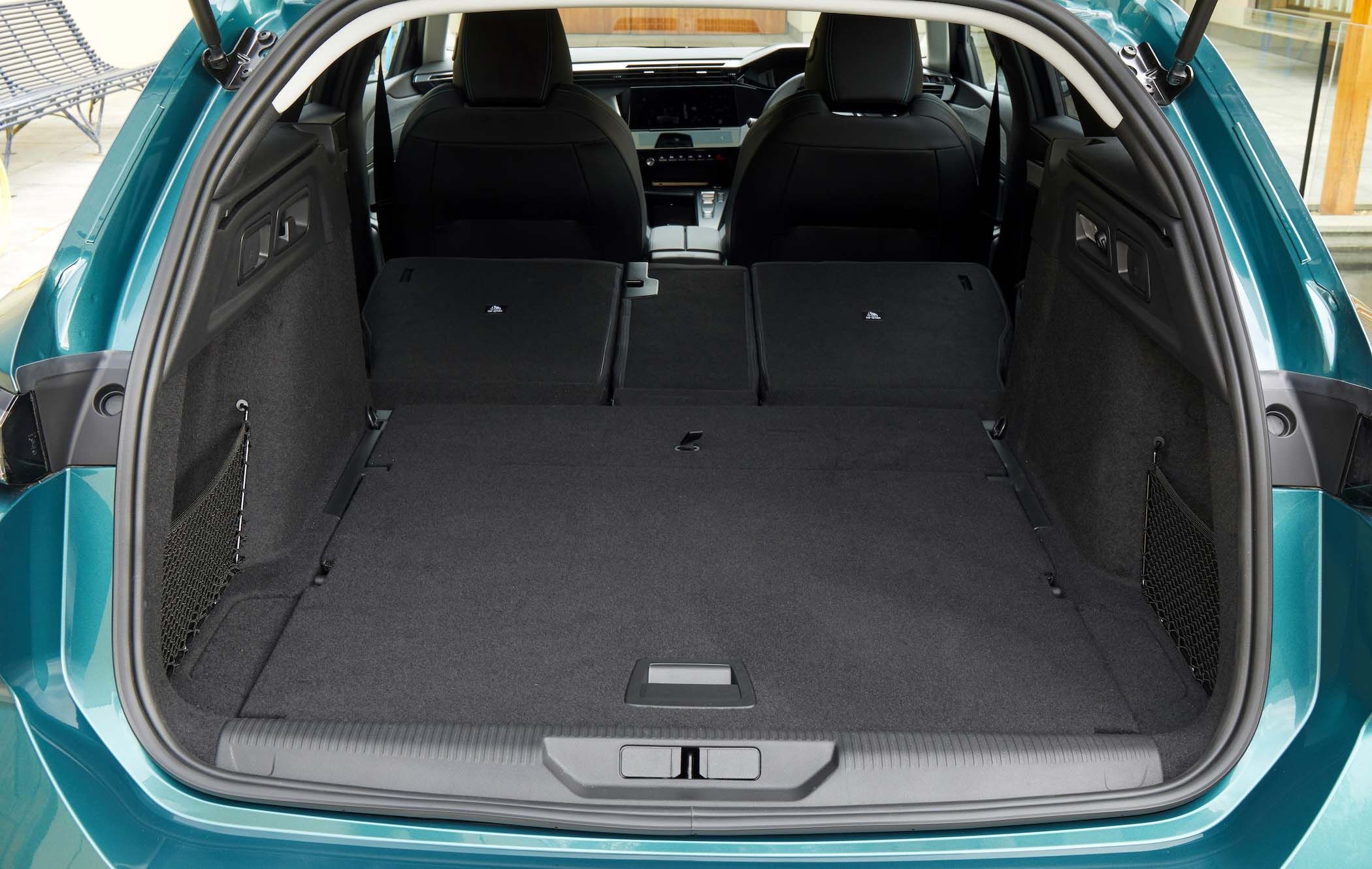Open boot of a Peugeot 308 SW showing spacious cargo area with rear seats folded down, revealing a flat and extended loading space.