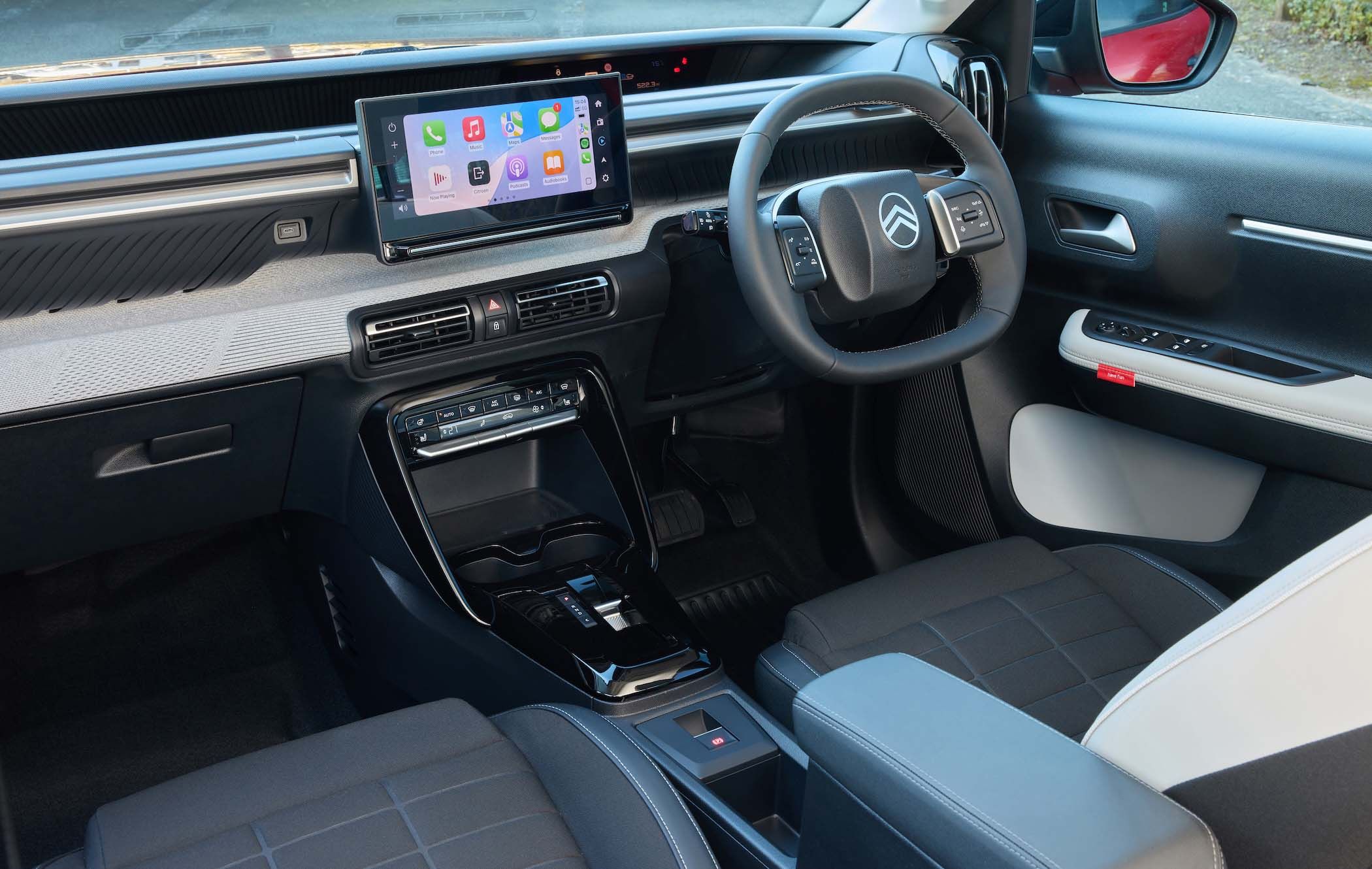 Citroën ë-C3 interior with a touchscreen display, steering wheel, and black seats. Features include digital controls and a sleek dashboard design.