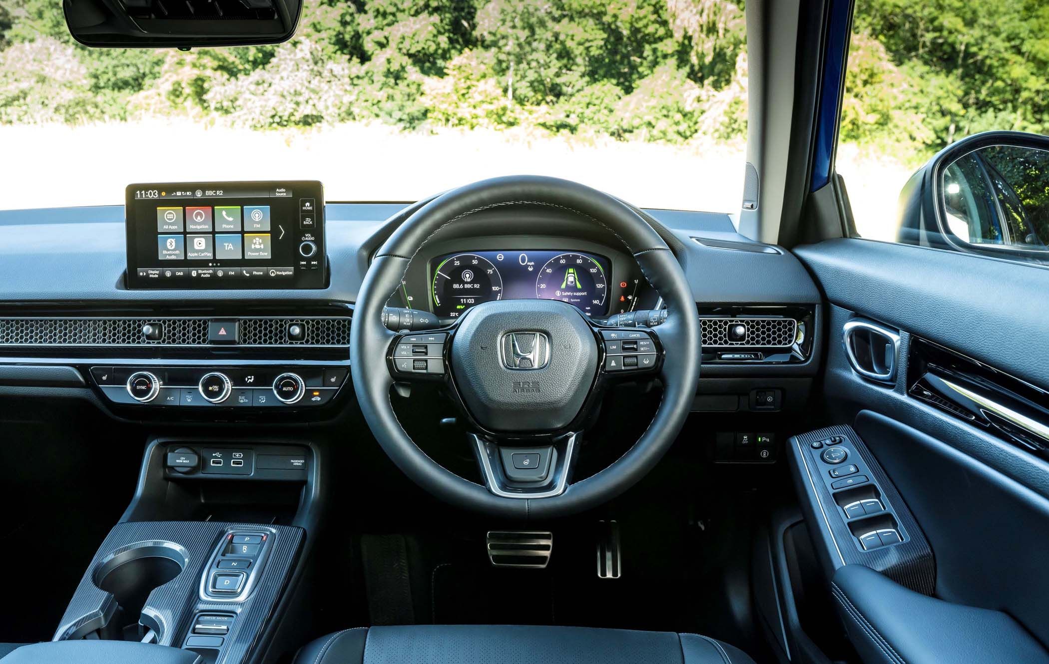 Interior view of a Honda Civic's cockpit featuring a Honda steering wheel, digital dashboard, touchscreen display, and control buttons on the door panel.