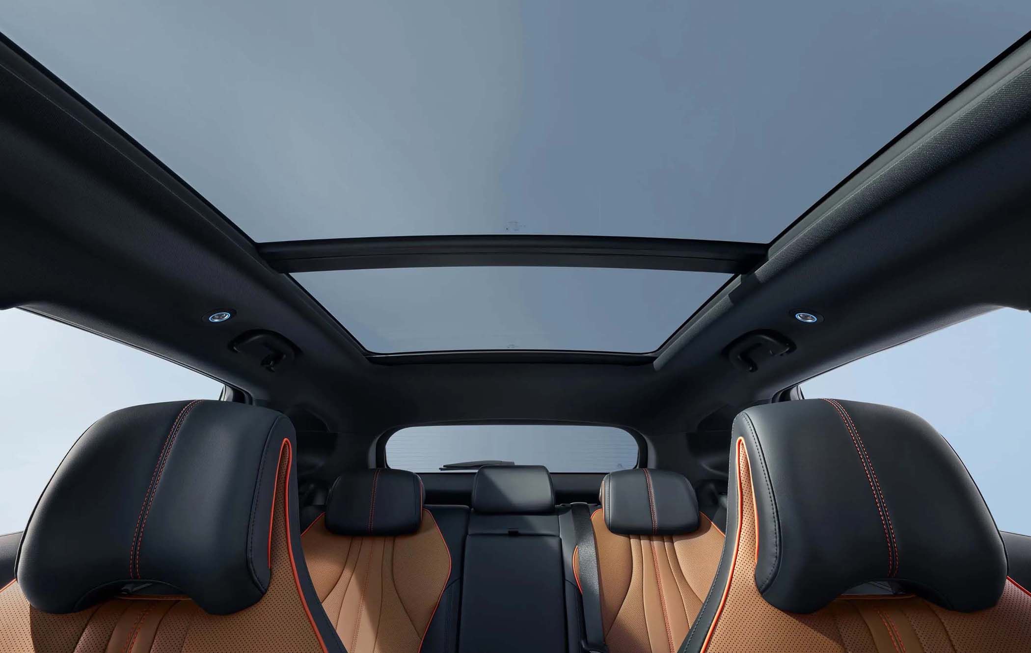 Interior view of a BYD SEAL U with orange and black leather seats, showcasing a panoramic sunroof against a clear sky.
