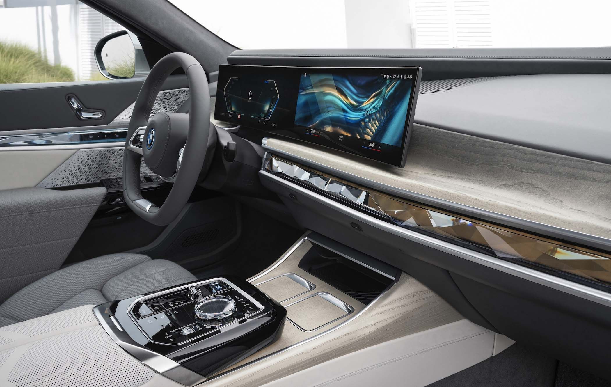 BMW 7 Series interior with sleek dashboard, digital displays, modern steering wheel, and a stylish centre console with wood and metallic accents.