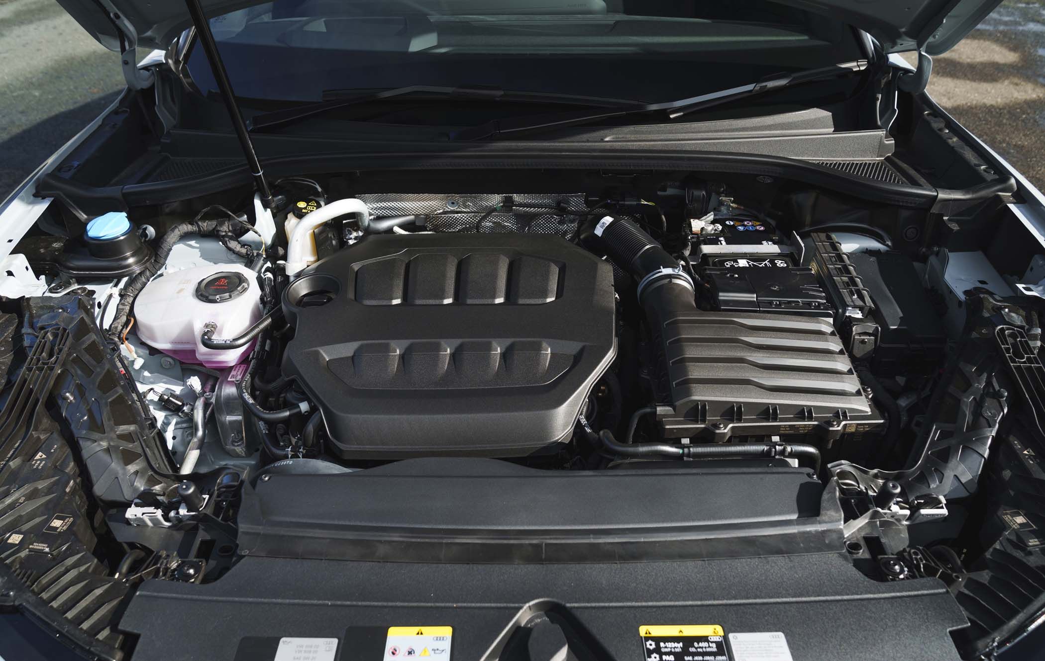 Close-up of an Audi Q3 engine bay showing various components, including the engine cover, air intake, and fluid reservoirs.
