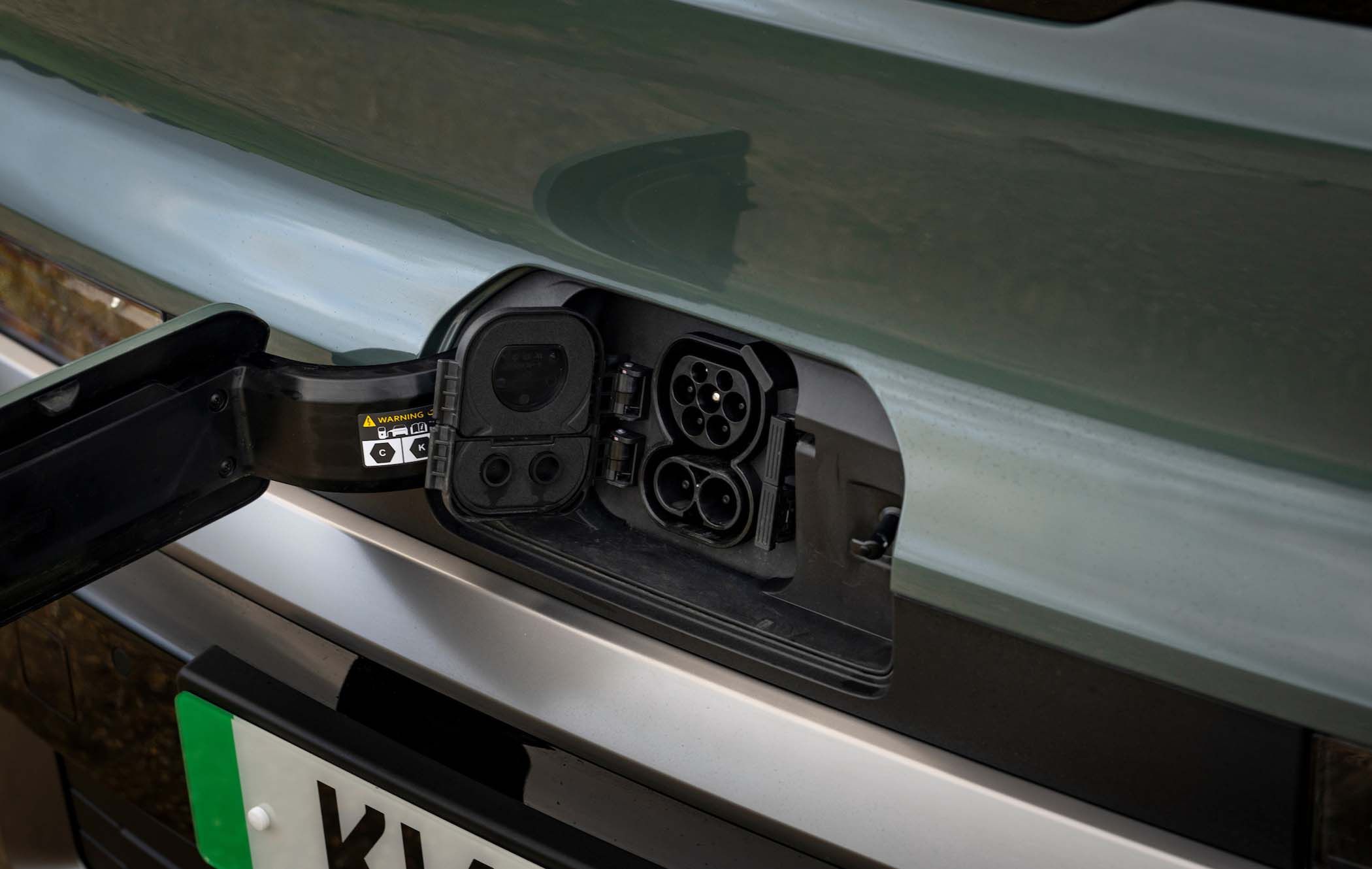 Close-up of an Kia PV5 Passenger's charging port with an open cover, revealing multiple connectors for charging.
