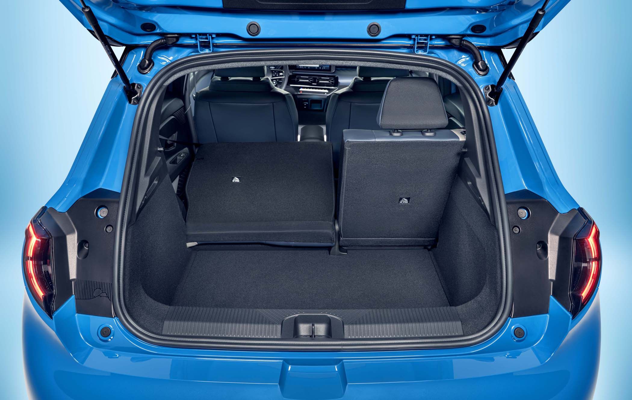 Open boot of a blue Nissan MICRA with rear seats partially folded, revealing a spacious luggage area and dashboard view.