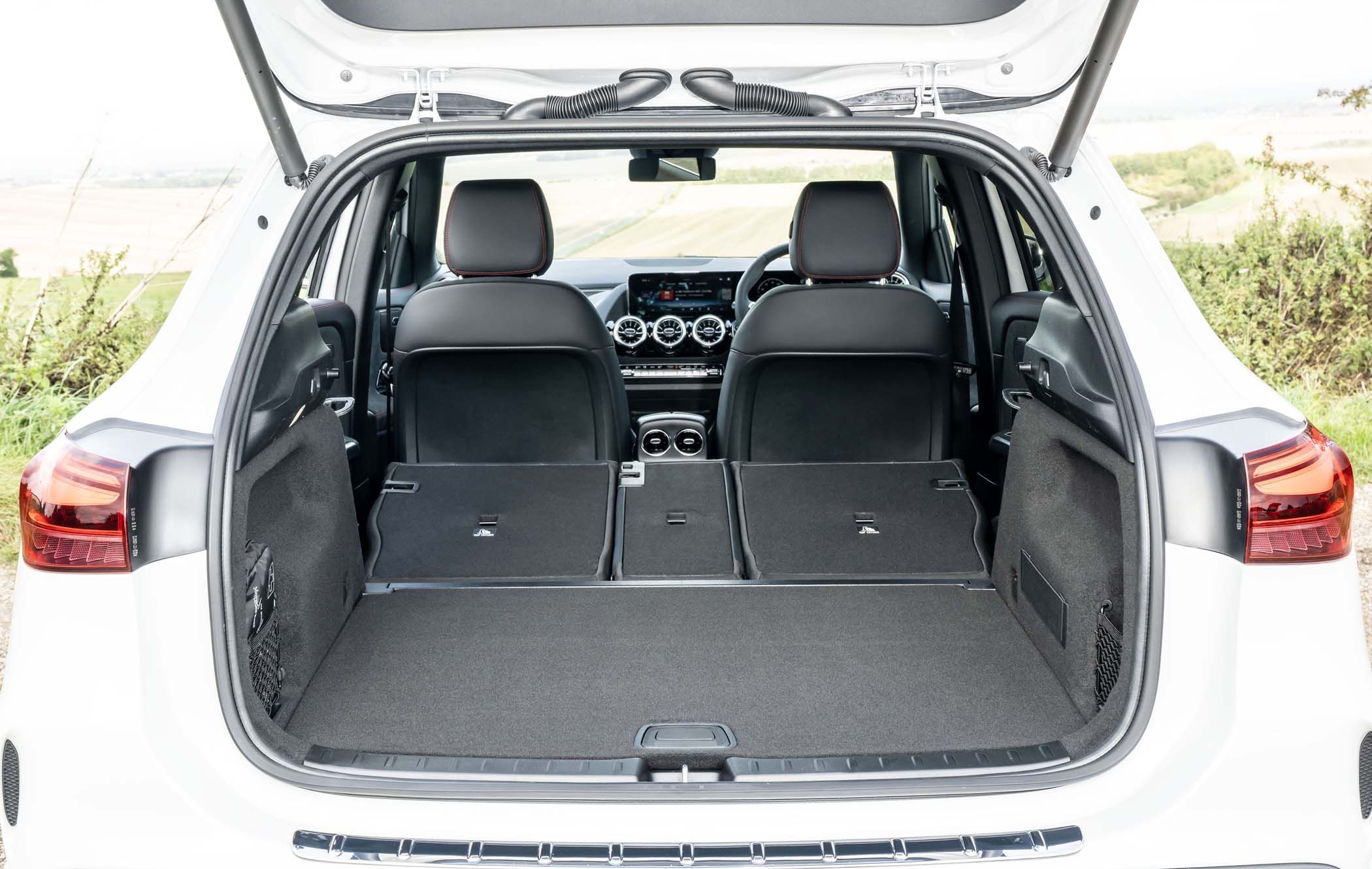 Mercedes GLA boot with rear seats folded down, showcasing a spacious and flat cargo area. The dashboard and front seats are visible through the open hatch.